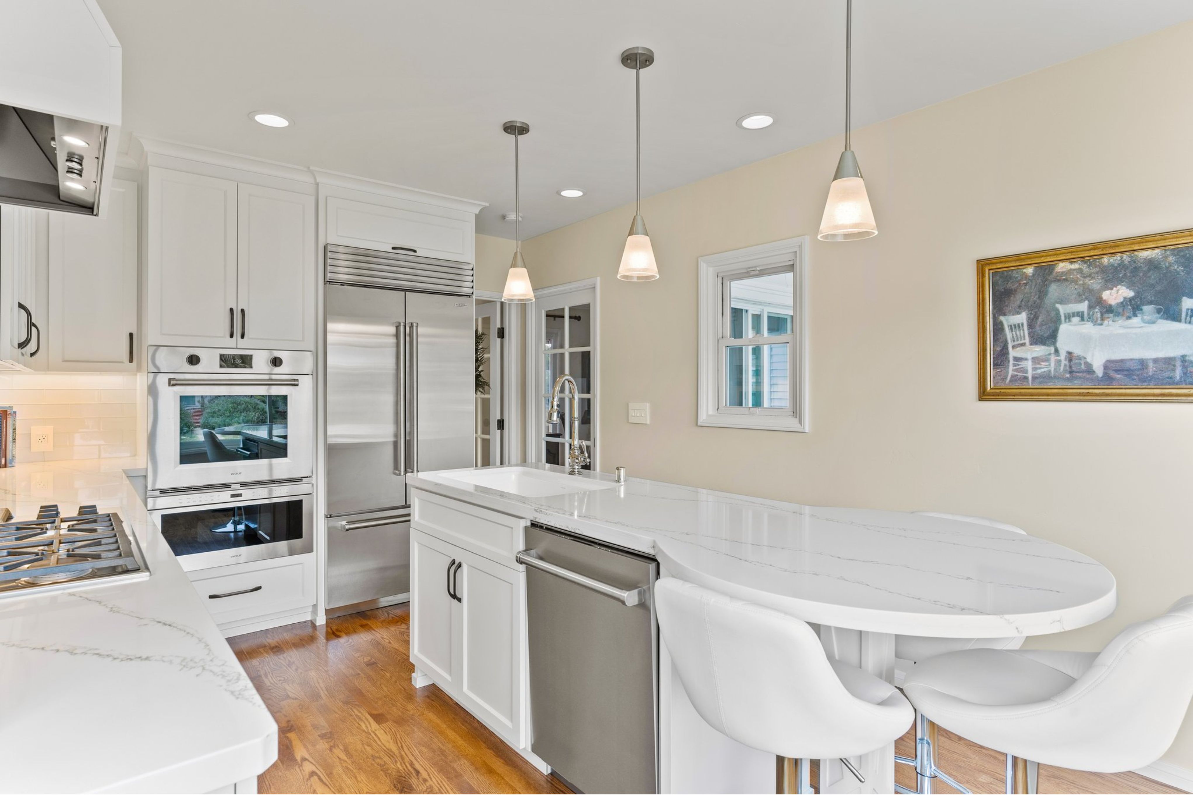 La Mesa kitchen remodel with white cabinetry, veined counters, peninsula seating, pendant lights and stainless appliances.