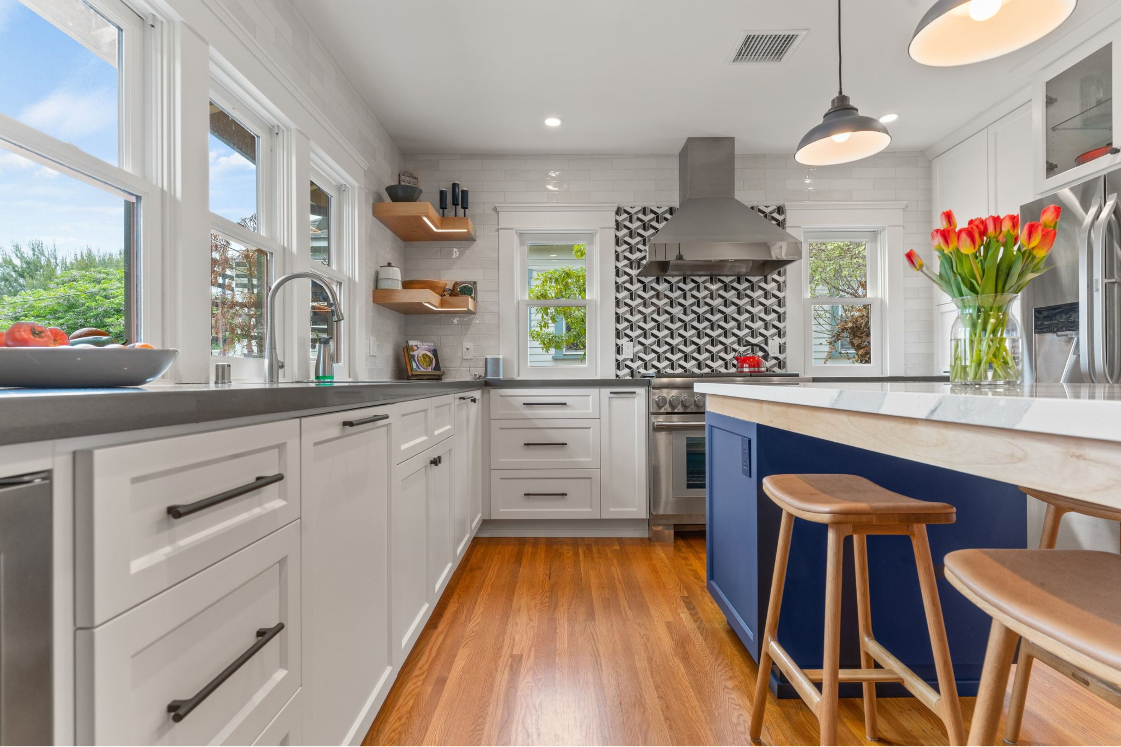 San Diego kitchen remodel with white cabinetry, blue island, quartz-look counters, pendant lights and hardwood flooring.