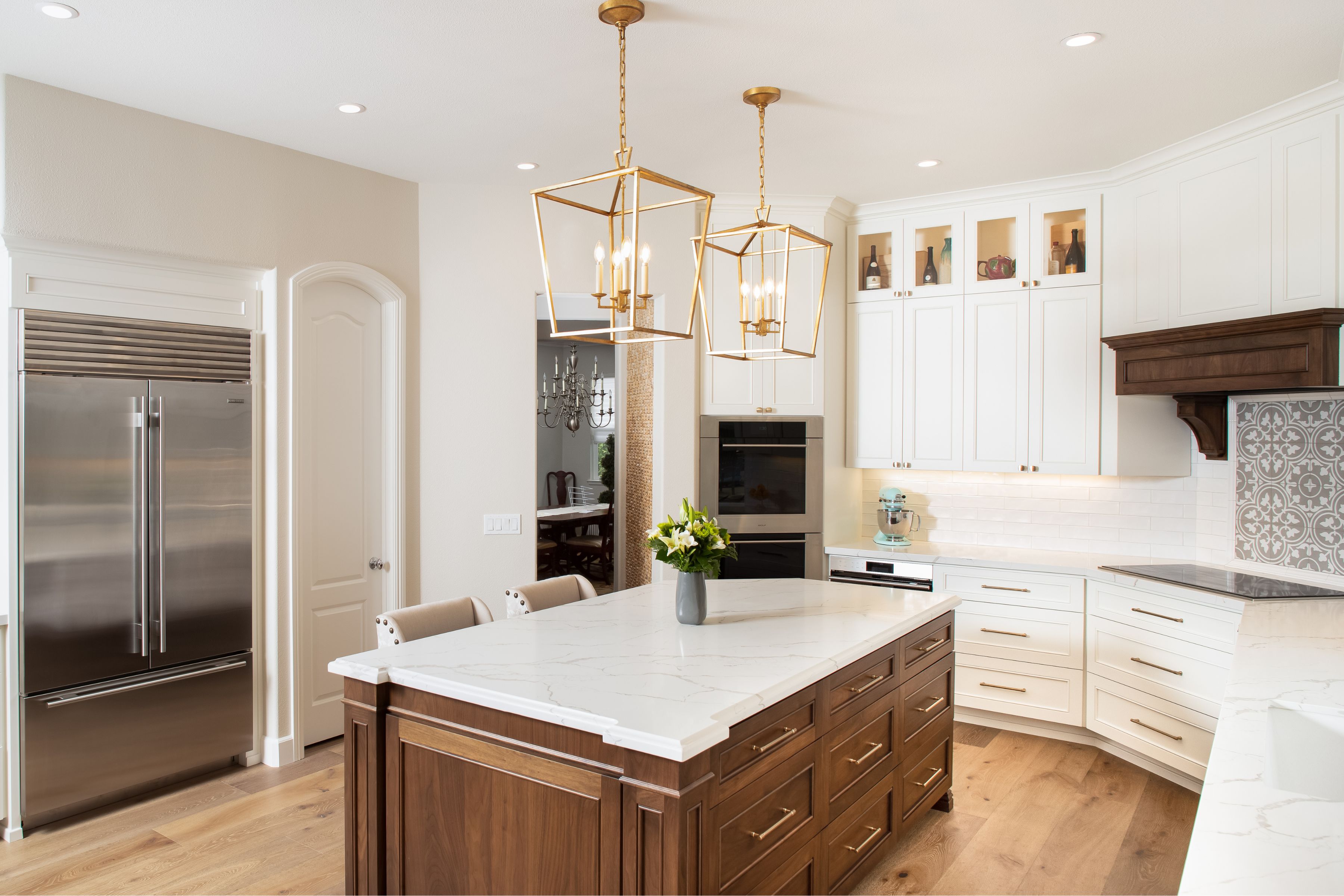 Carlsbad kitchen remodel with wood island, white cabinetry, veined quartz counters and brass lantern pendants.