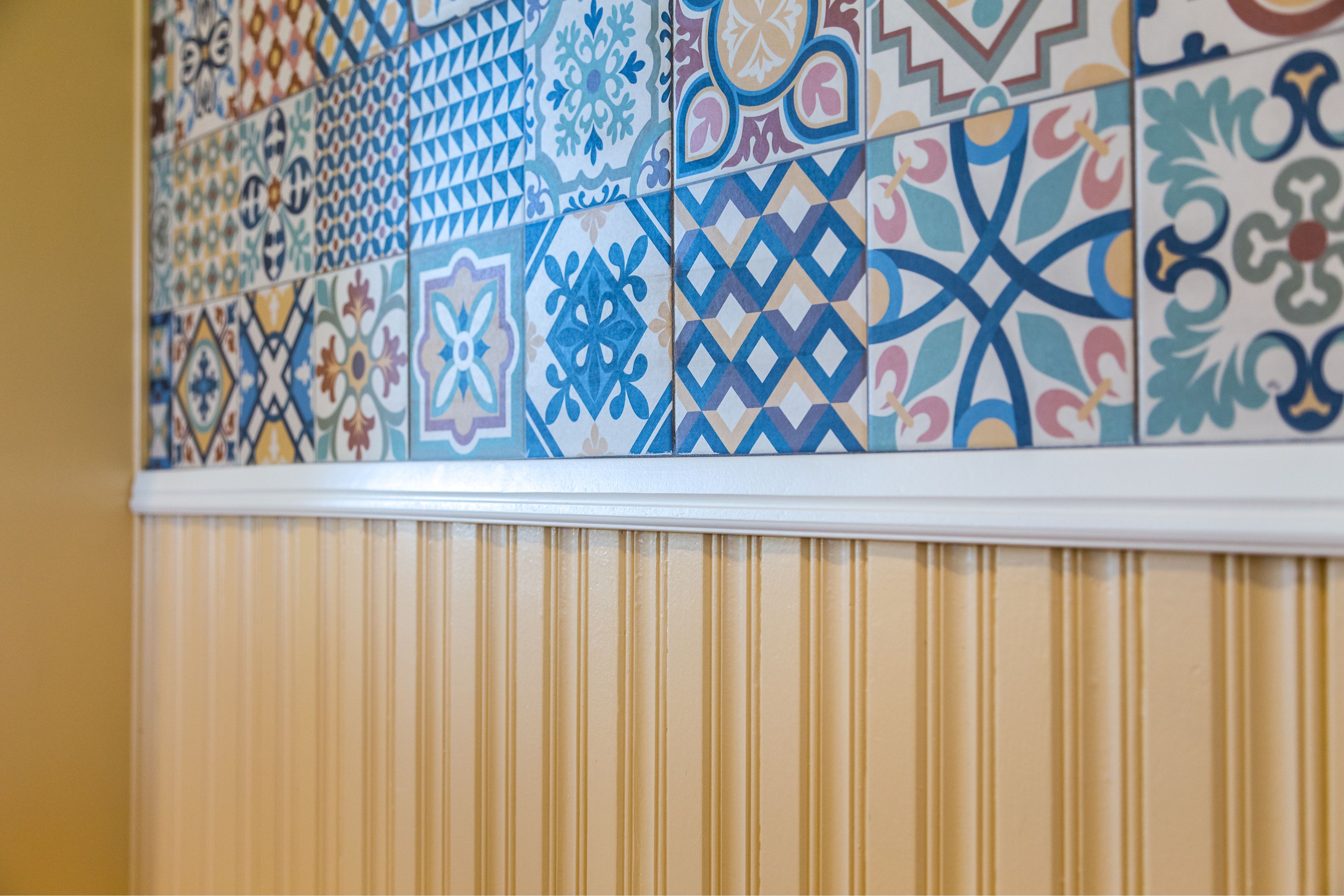 Colorful patterned tile wall above cream beadboard wainscoting in the National City kitchen remodel