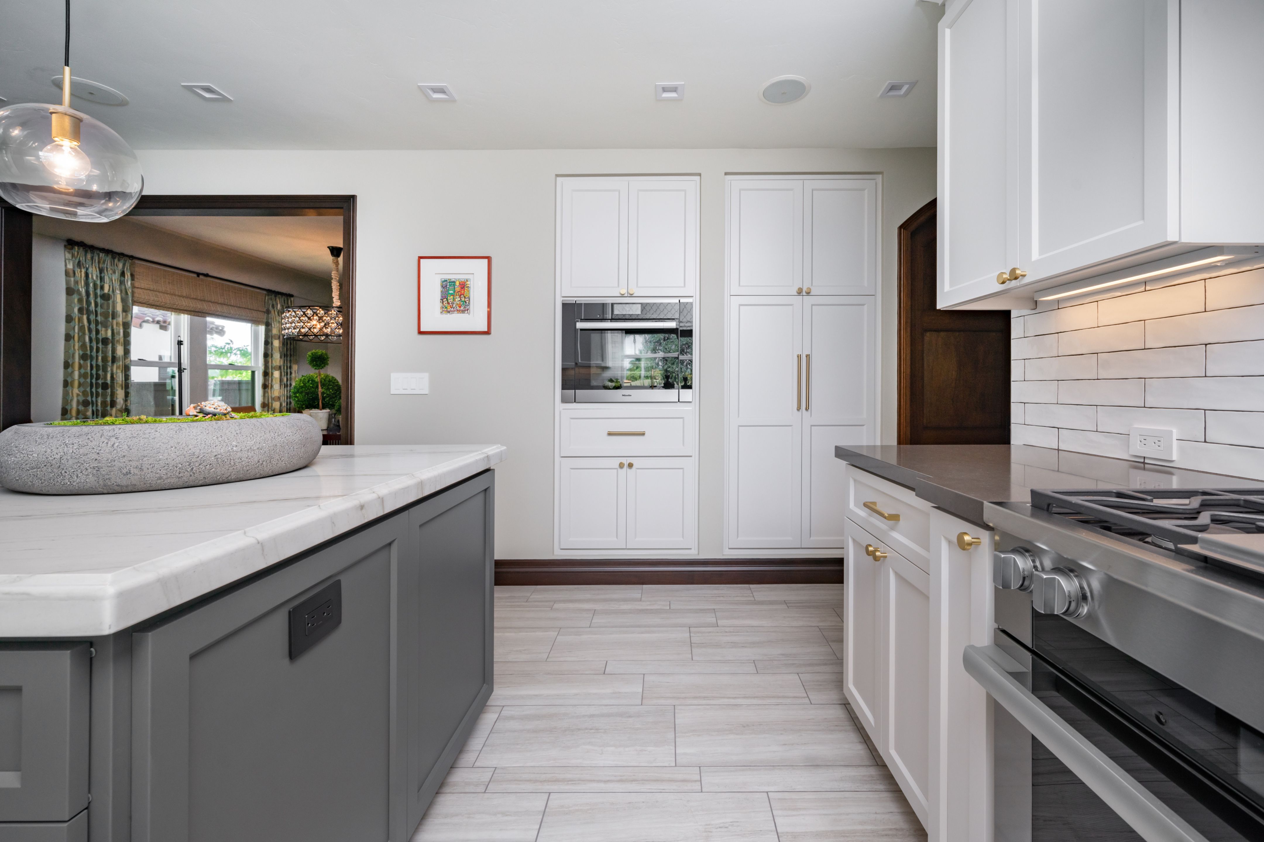 Normal Heights kitchen with gray island, white cabinetry, brass hardware, marble-look counters and tile flooring