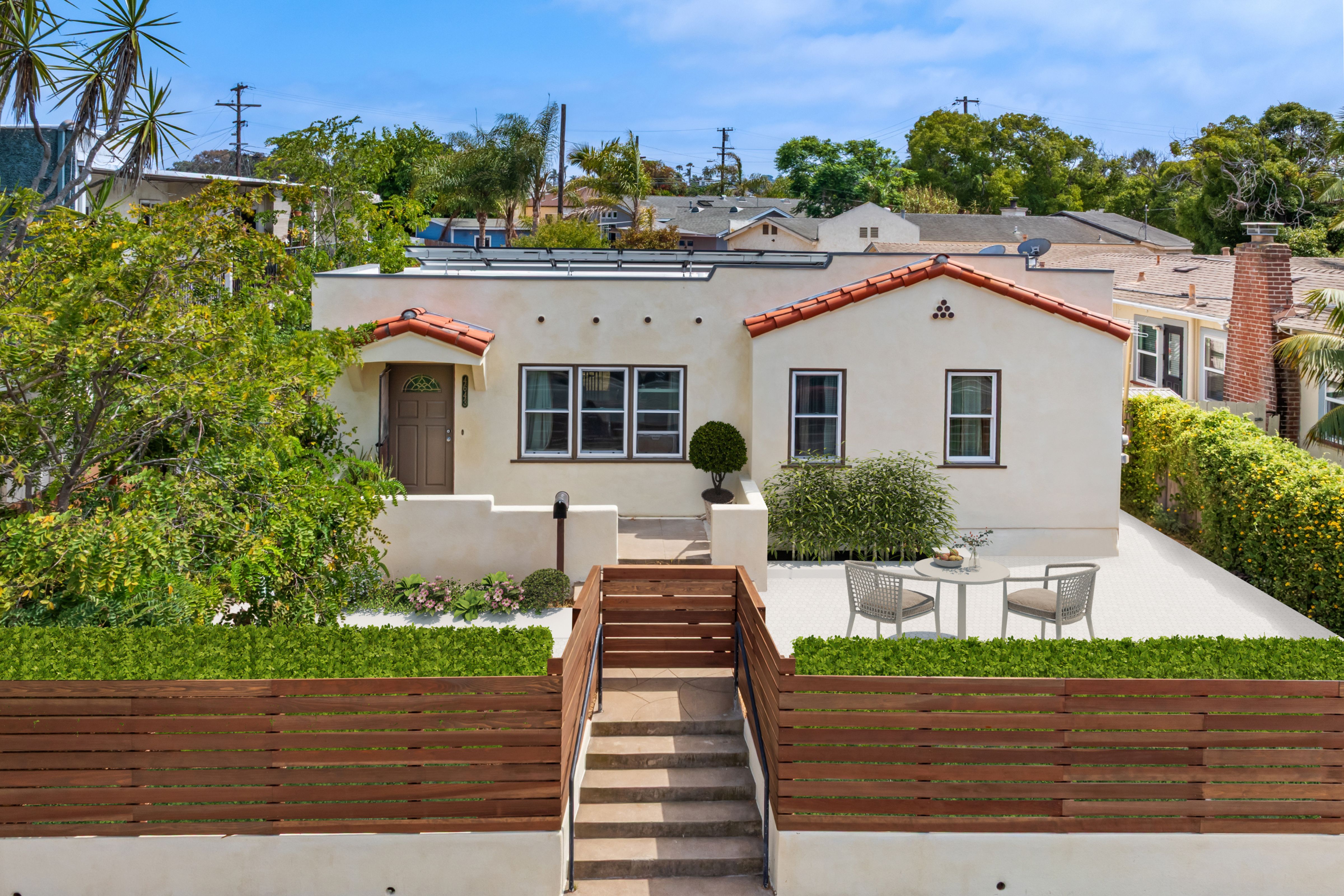 Stucco home exterior with red tile roof, front patio, wood fencing and landscaped entry.