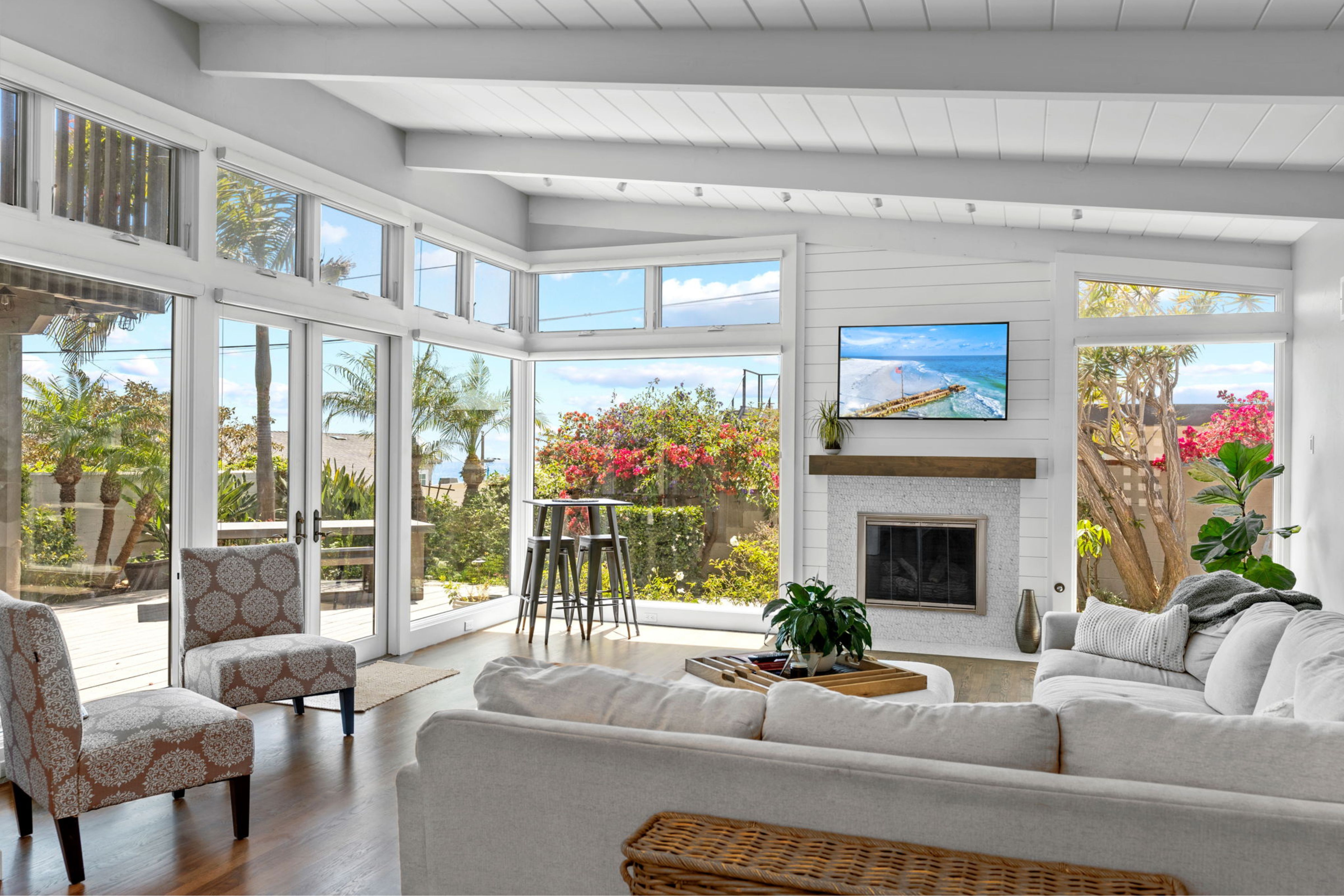 La Jolla living room with refinished wood floors, remodeled fireplace, exposed beams and expansive ocean-facing windows.