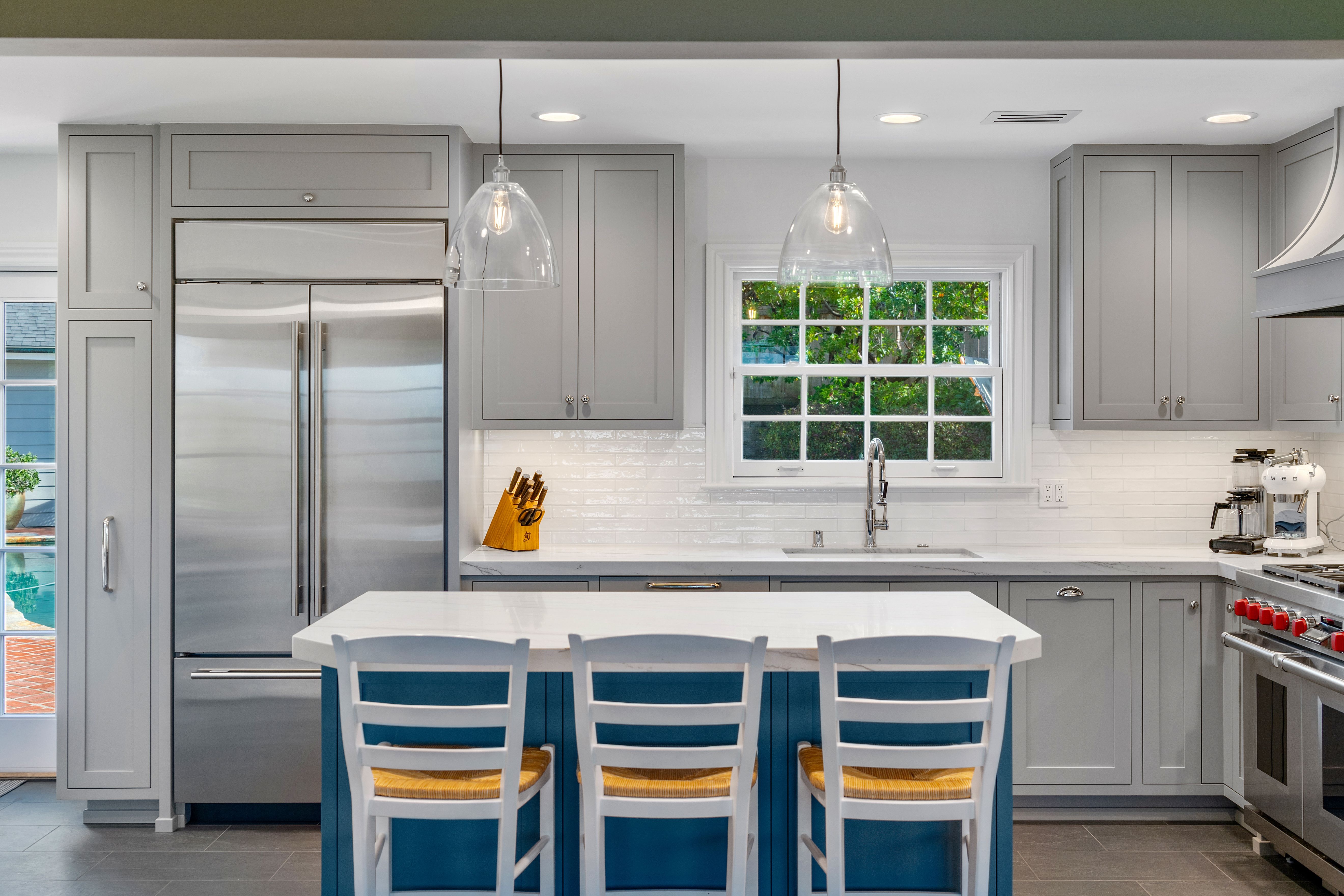 Del Mar kitchen remodel with painted inset cabinetry, blue island, pendant lights, stainless appliances and tile backsplash.