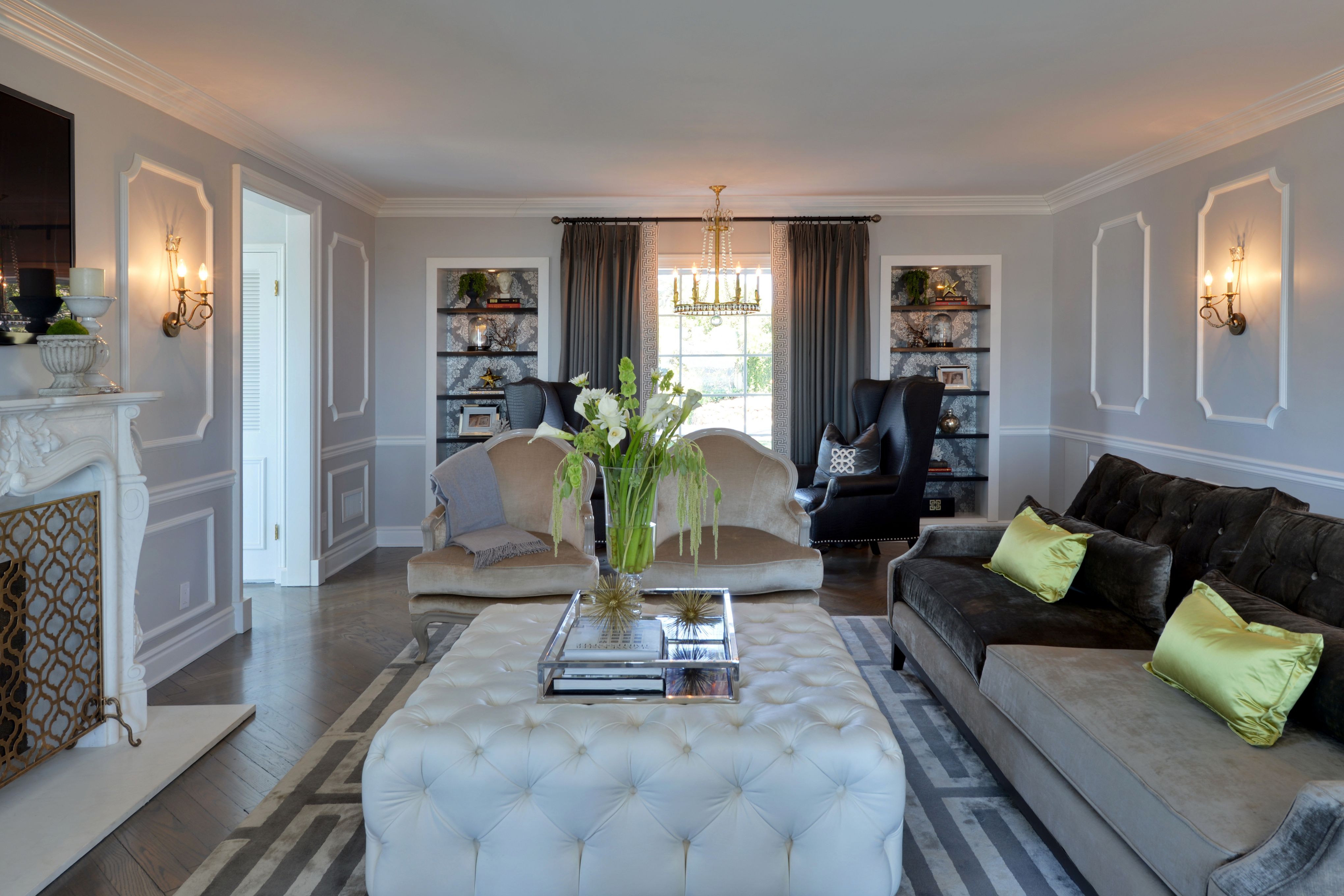 Formal living room with gray paneled walls, crown molding, dark wood floors, built-in shelves and decorative fireplace.