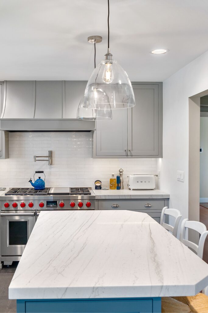 Del Mar kitchen remodel with blue island, gray inset cabinetry, white counters, glass pendants and stainless range.