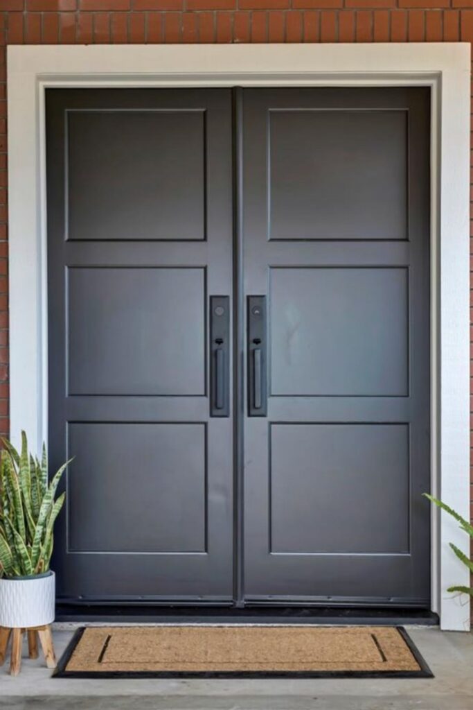 Dark paneled double entry doors with black hardware, white trim and brick exterior surround.