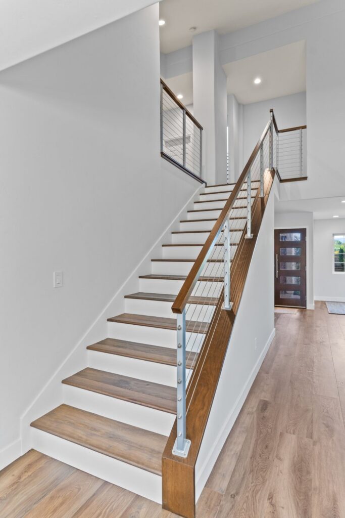 Remodeled staircase with wood treads, white risers, cable railing and wood handrails in Del Mar home
