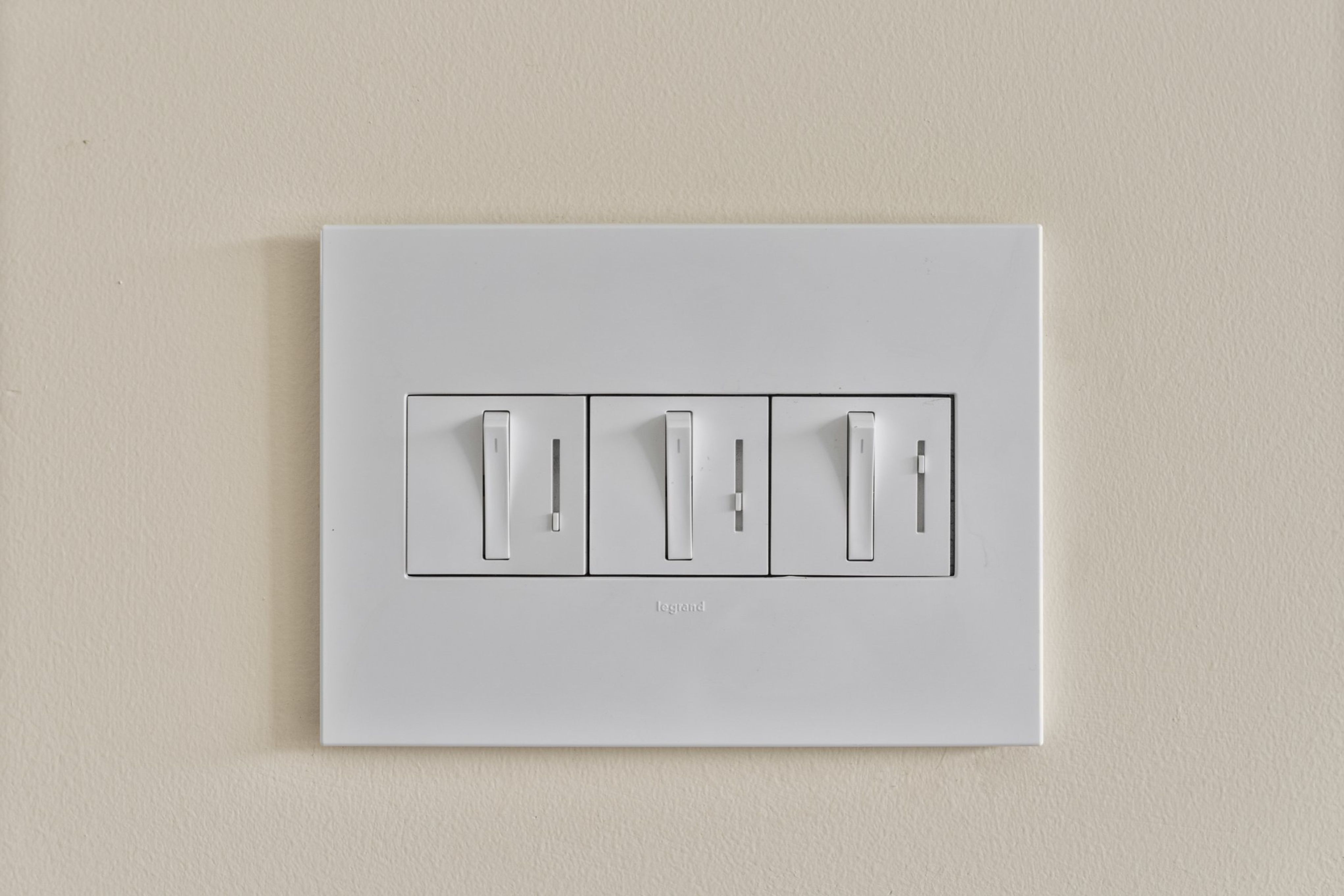 Three white dimmer switches provide adjustable lighting control on a neutral wall in the remodeled La Mesa home.