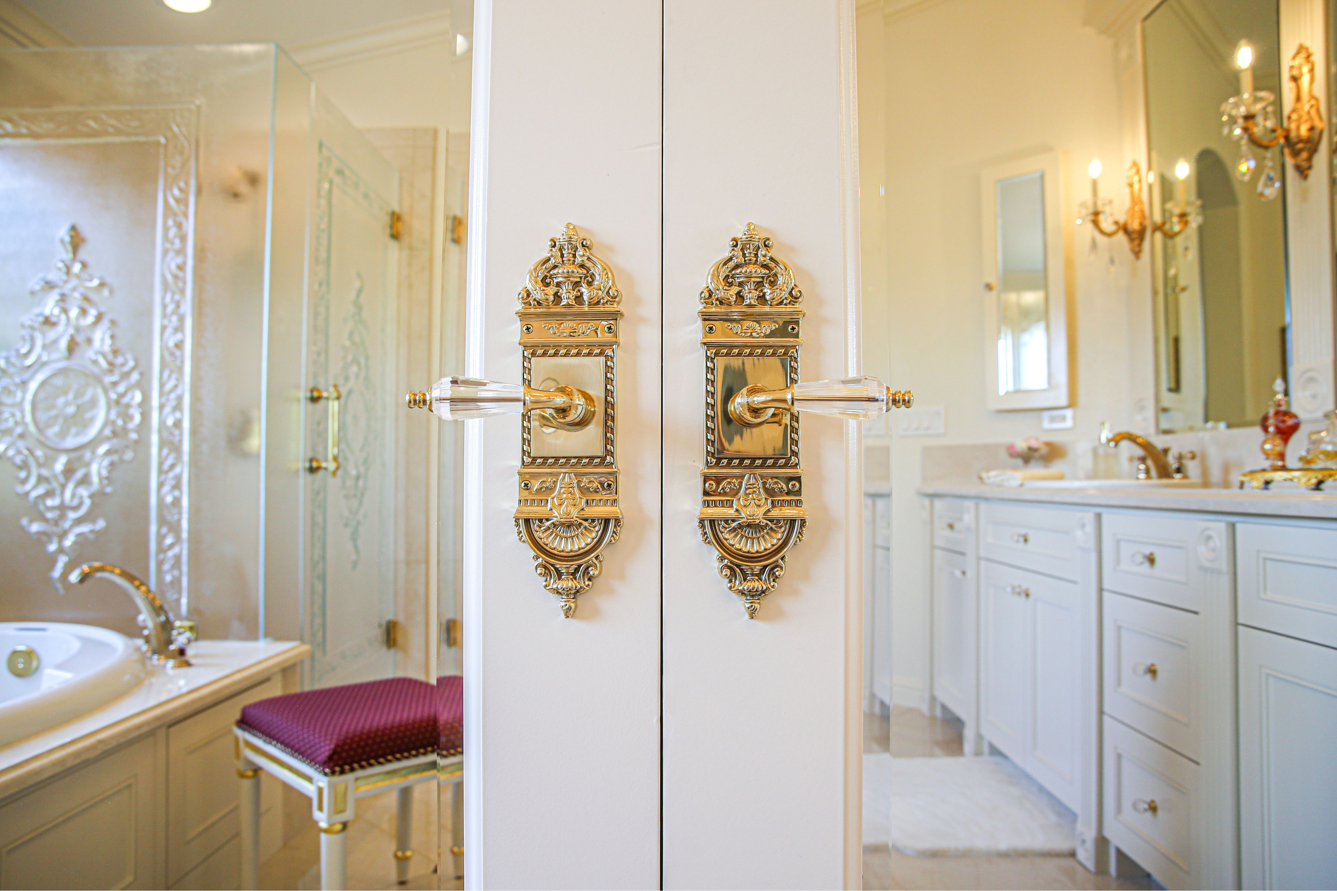 Ornate gold and crystal door hardware opens to a master bath with double vanity, soaking tub and glass shower.