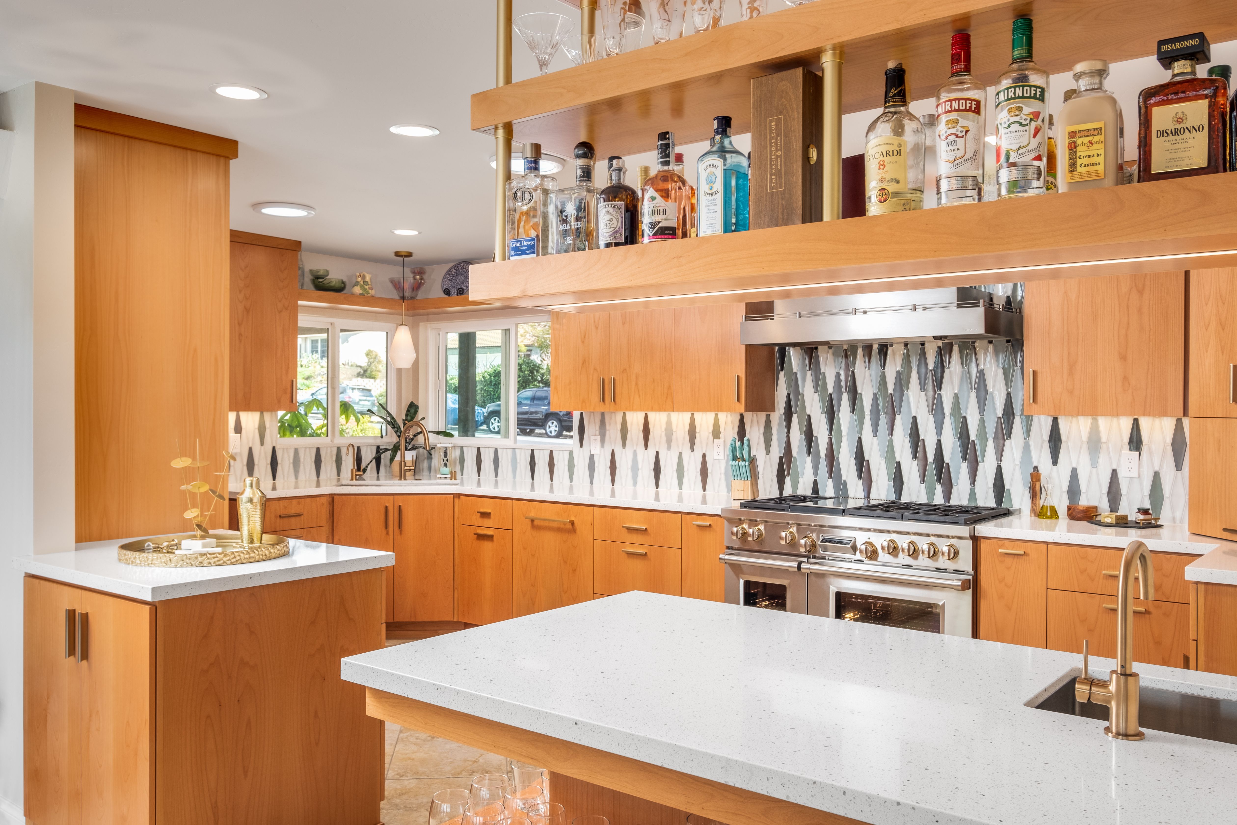 La Mesa kitchen with warm wood cabinetry, white counters, geometric backsplash, range and suspended bar shelving