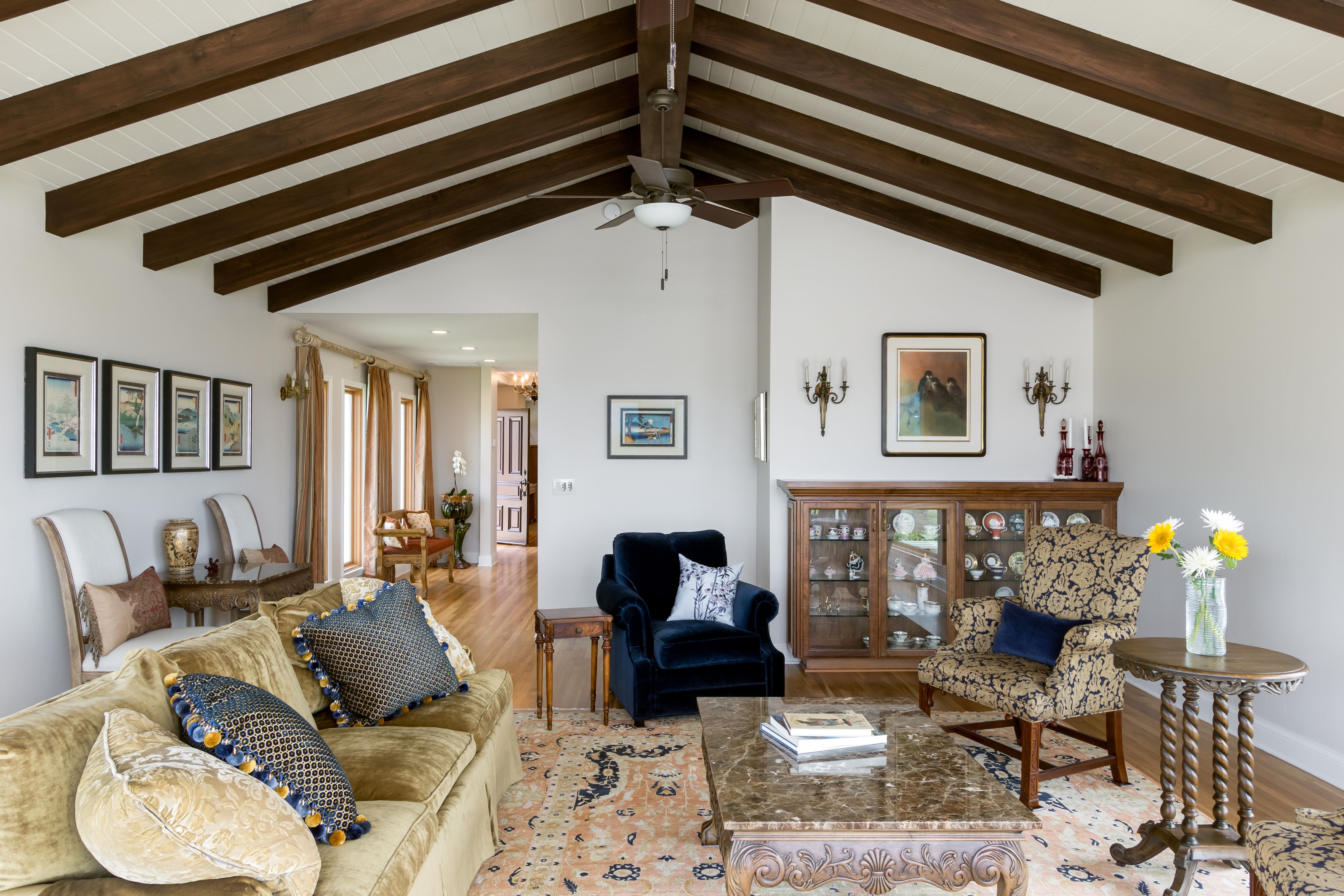 Remodeled living room with vaulted white ceiling, exposed wood beams, hardwood floors and open circulation.