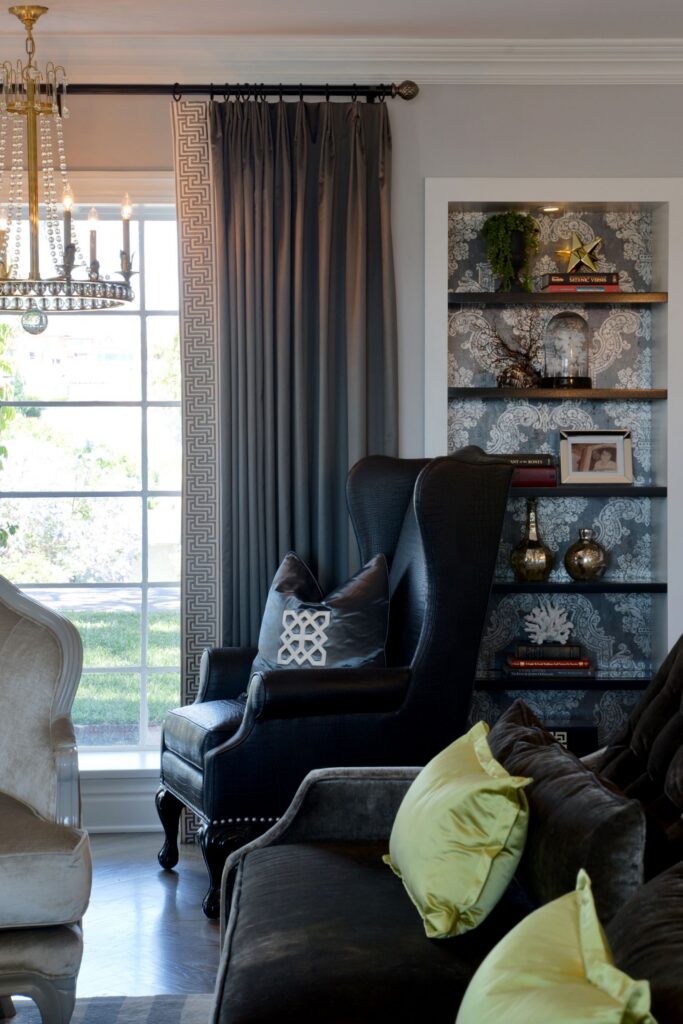Living room with dark wingback chair, patterned built-in display niche, floor-length drapery and crown molding