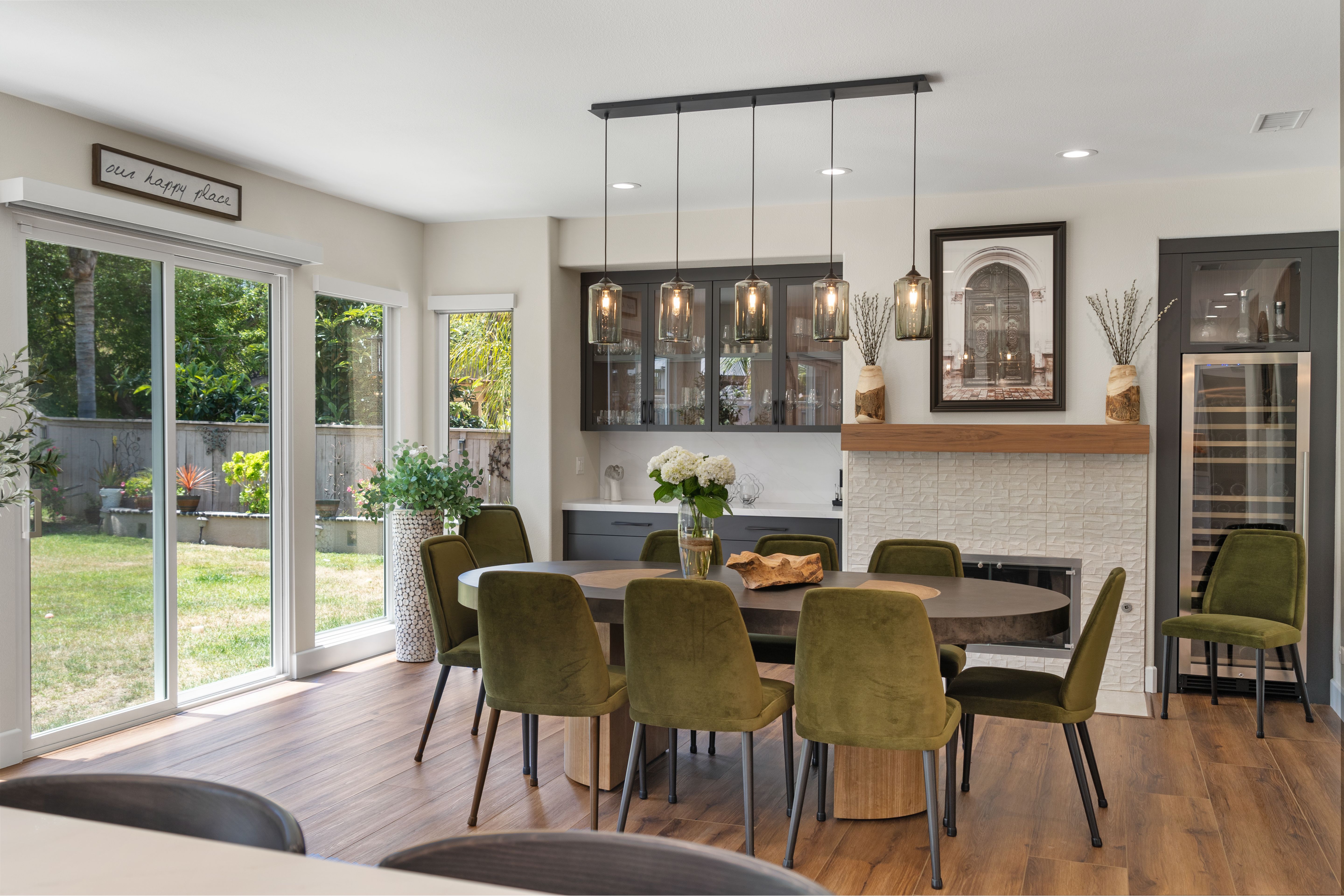 Dining room with fireplace reface, wood mantel, glass-front cabinetry, pendant lights and wide patio doors