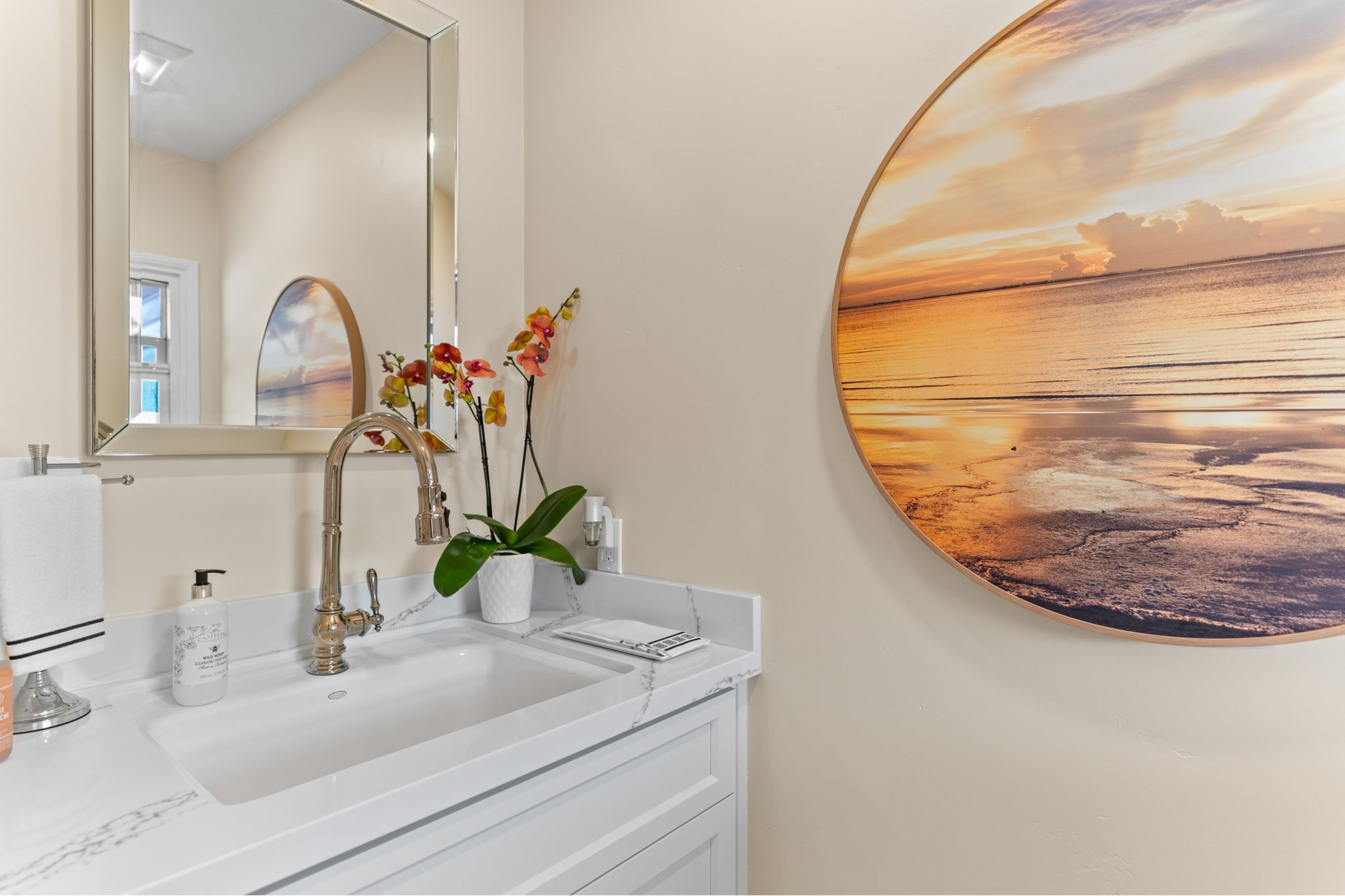 Remodeled half bath with white vanity, veined countertop, polished metal faucet, framed mirror and rectangular sink.