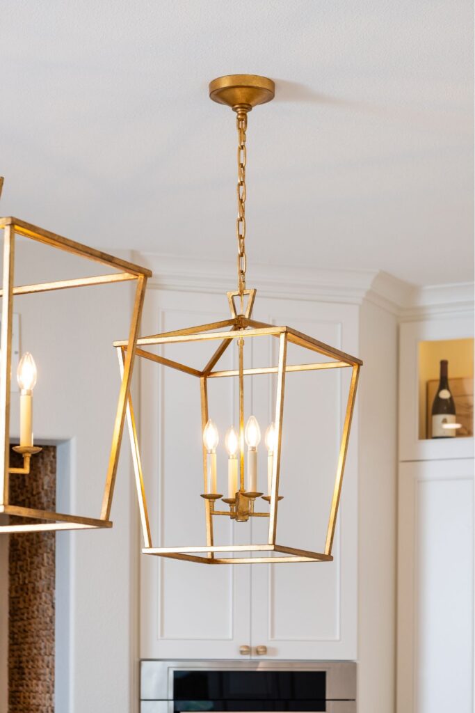 Brass open-frame lantern pendant above white kitchen cabinetry in the Carlsbad remodel.