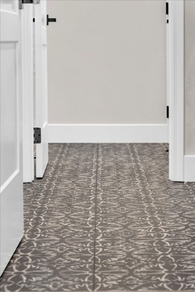Hallway with gray patterned tile flooring, white paneled doors and contrasting black hardware.