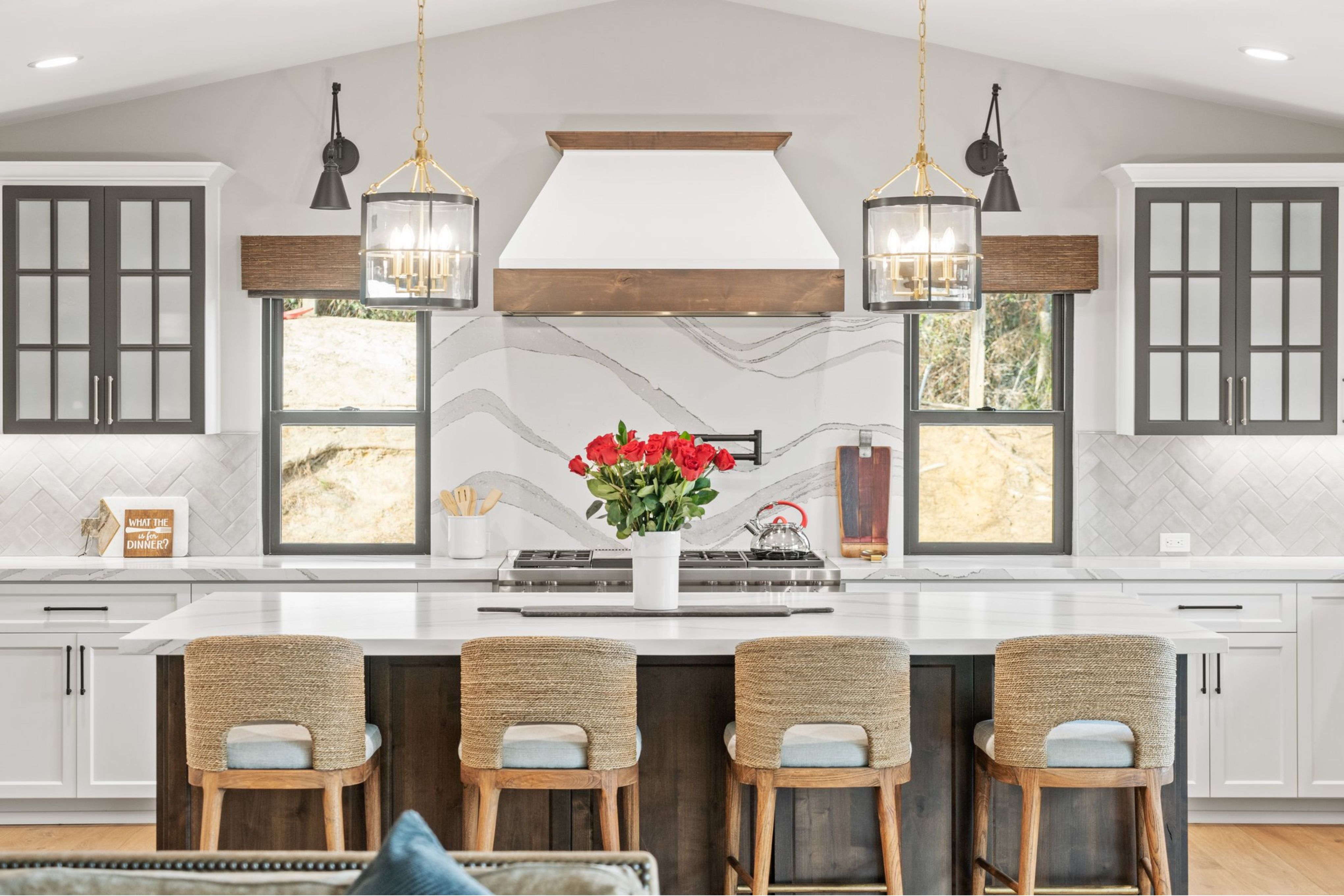 Encinitas kitchen with large dark wood island, four counter stools, quartz surfaces and symmetrical pendant lighting.