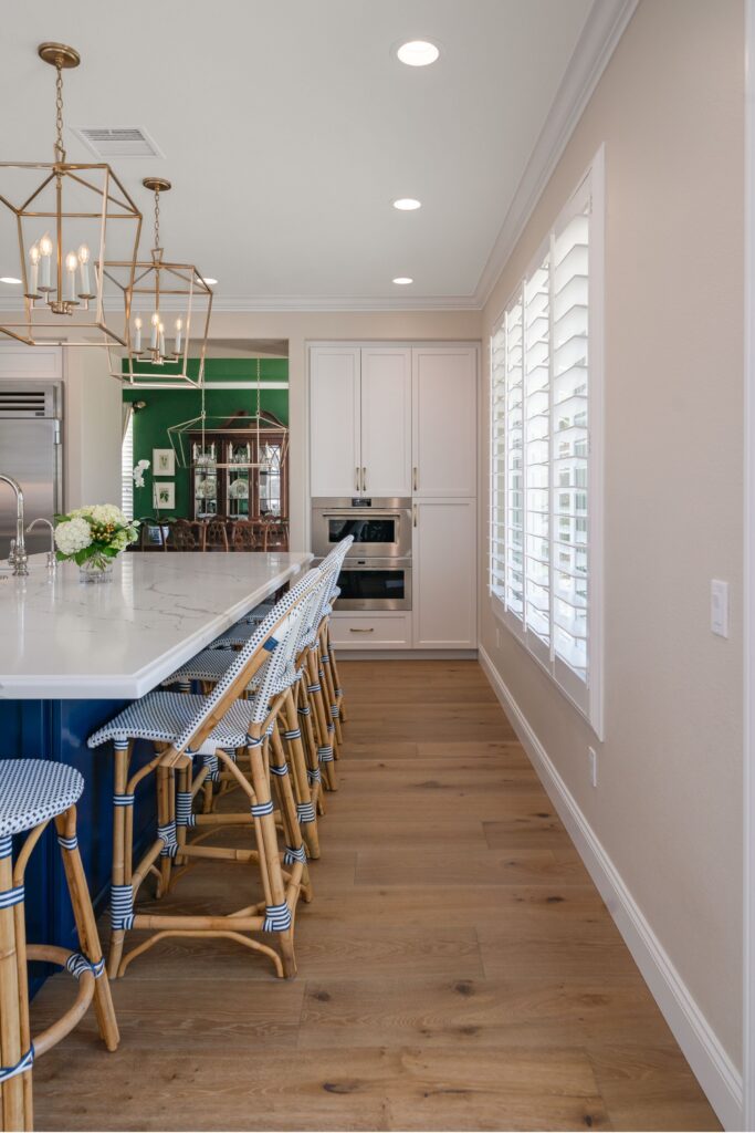 Carmel Valley kitchen remodel with blue island seating, white cabinetry, brass pendants and wide-plank wood flooring.