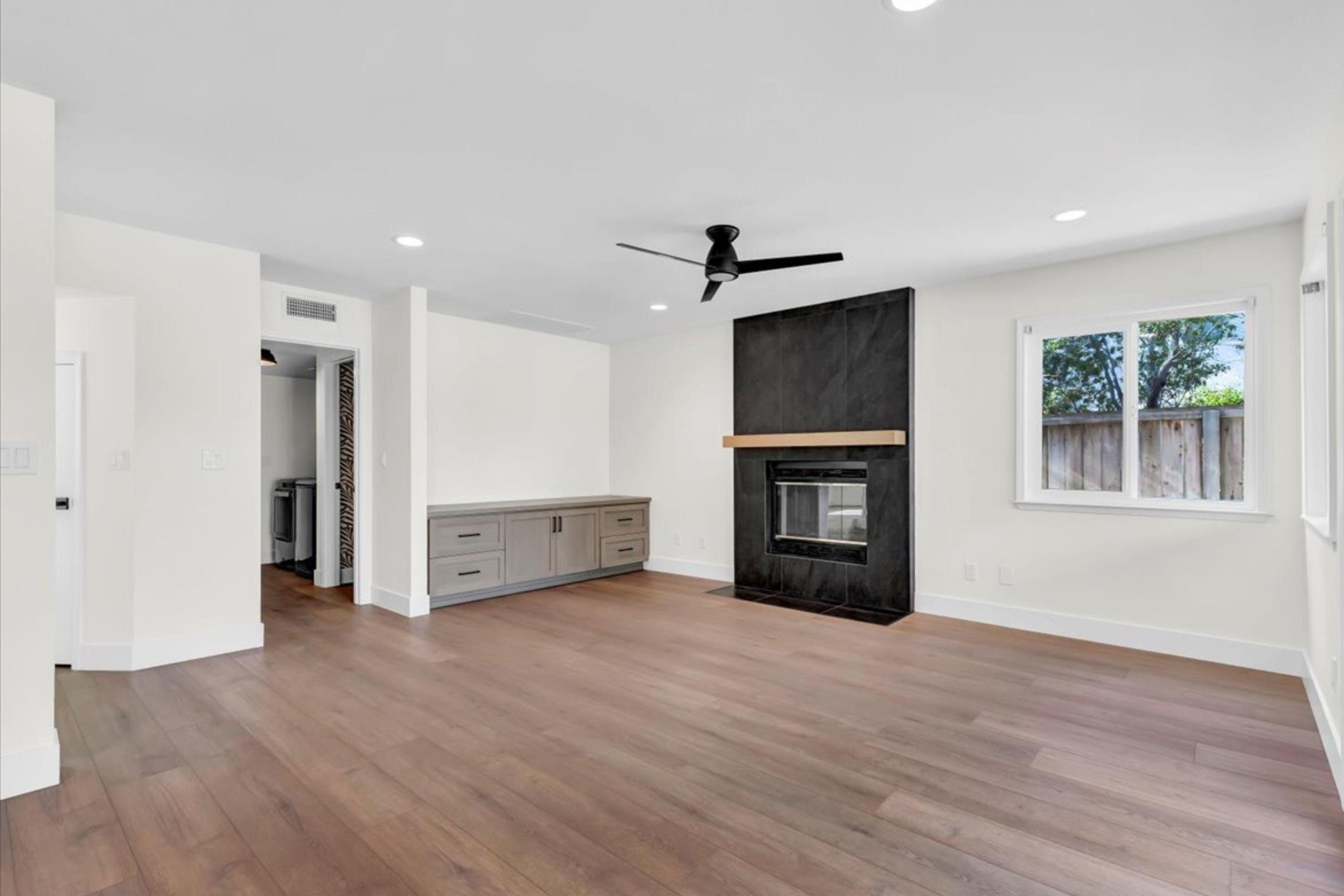 Encinitas remodeled living room with wood flooring, built-in cabinetry and dark tile fireplace with wood mantel.