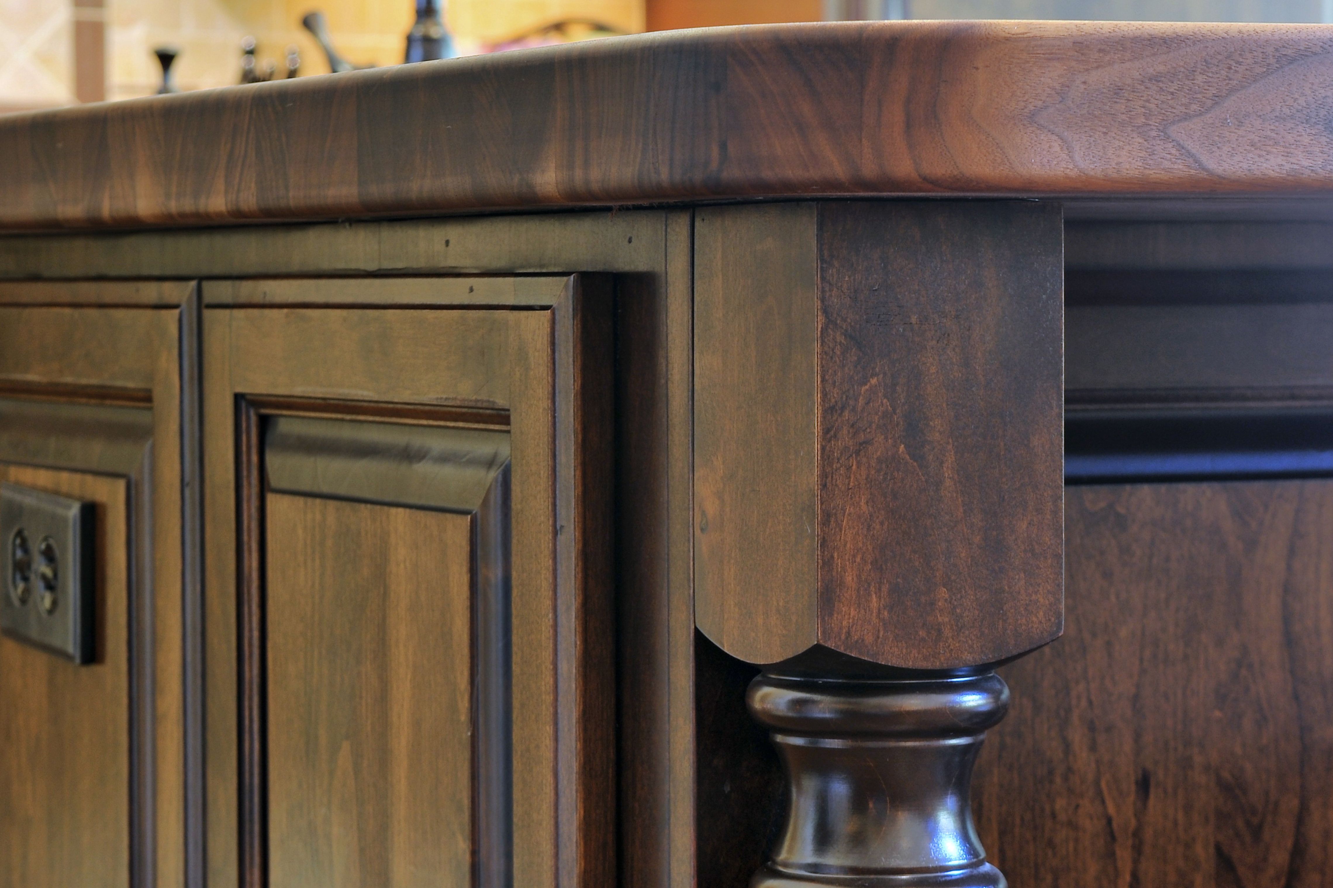 Close-up of dark wood island cabinetry with detailed millwork and thick walnut butcher-block countertop
