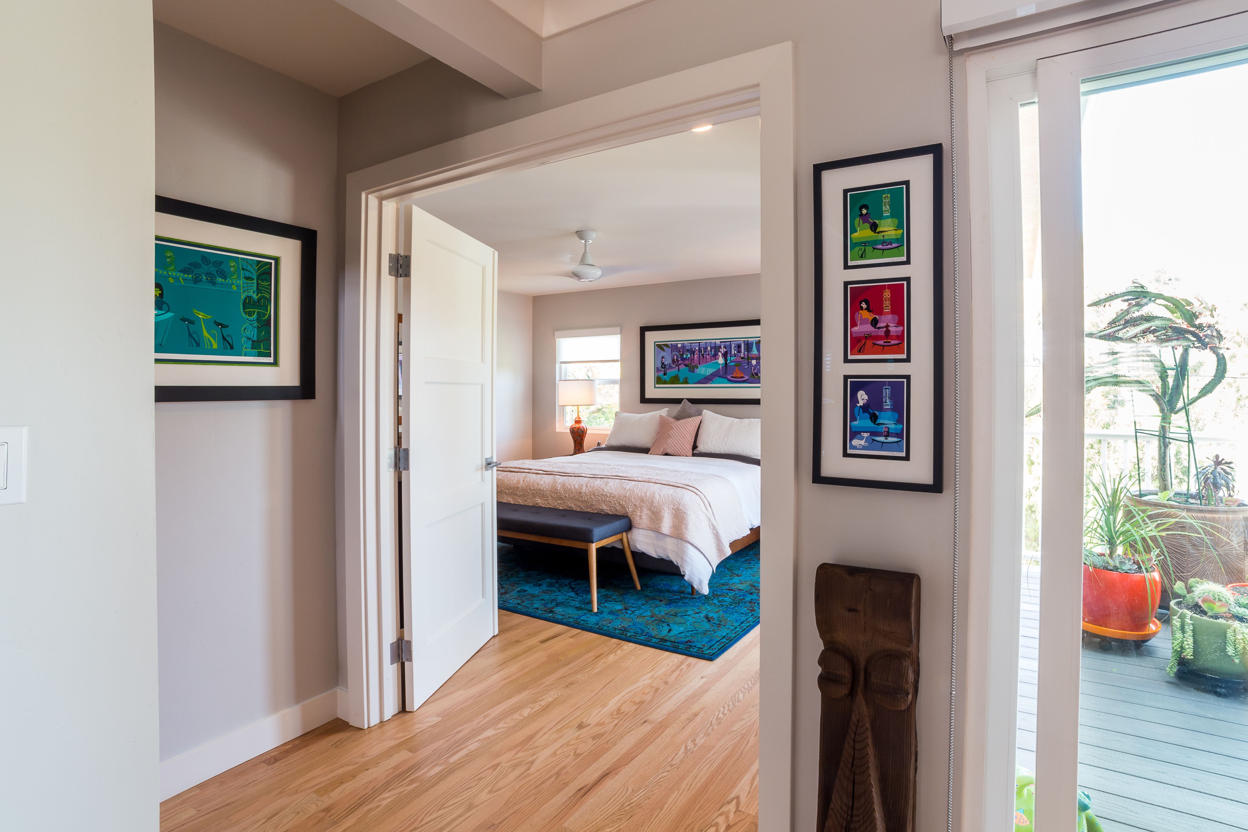 Primary bedroom entrance with wide doorway, hardwood flooring, neutral walls and glass doors opening to an outdoor deck