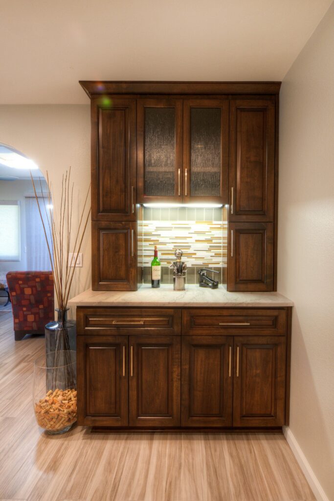 Built-in beverage station with dark wood cabinetry, textured glass doors, mosaic backsplash and under-cabinet lighting.