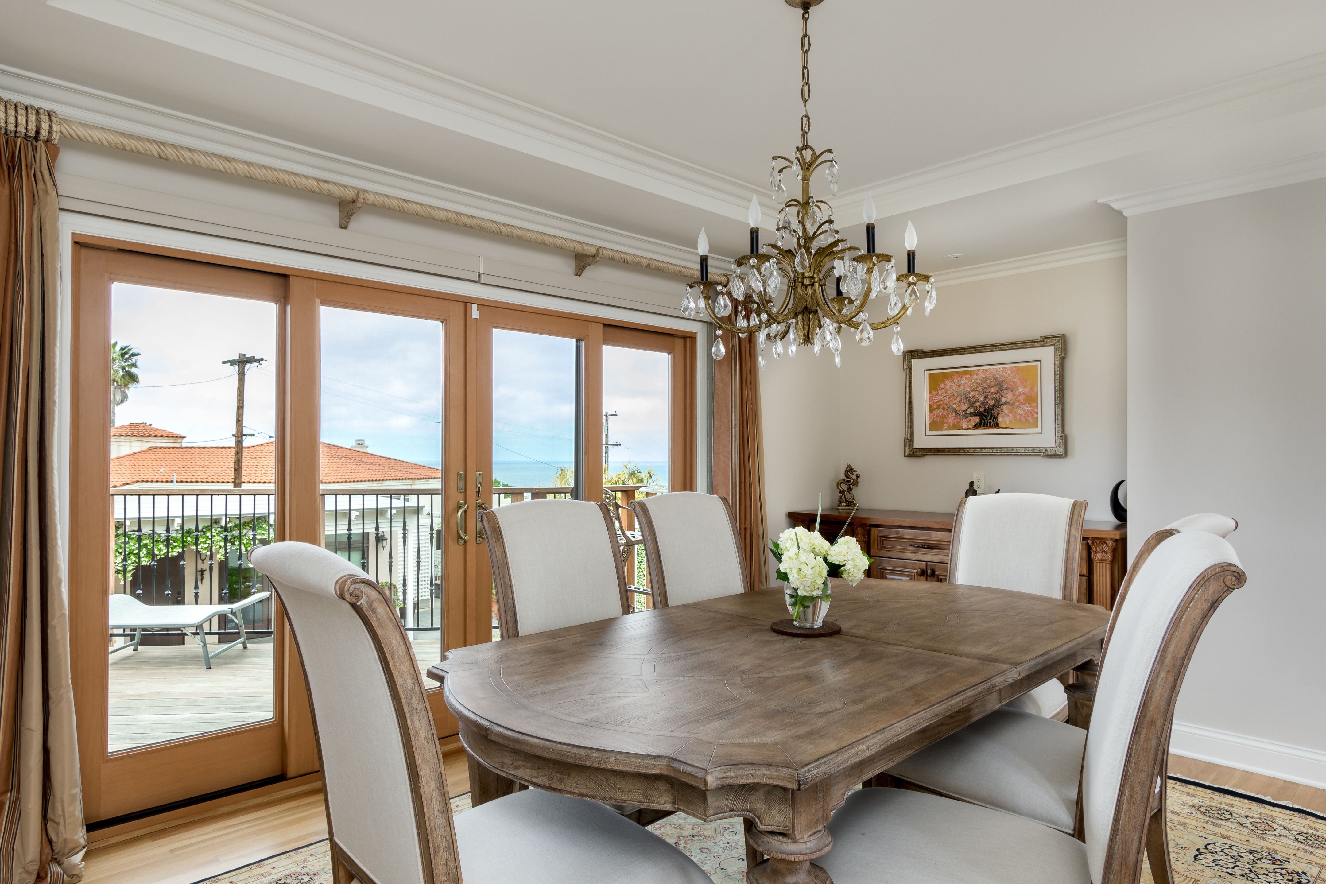 Dining room with hardwood floors, crown molding and wood-framed glass doors opening toward the rear deck.