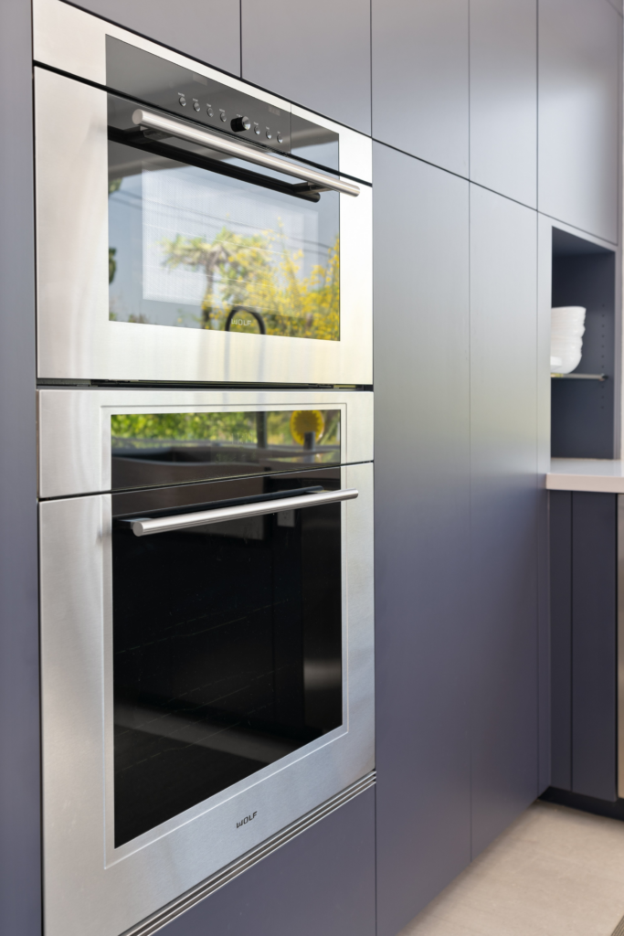 Built-in stainless steel wall ovens integrated into floor-to-ceiling dark kitchen cabinetry.