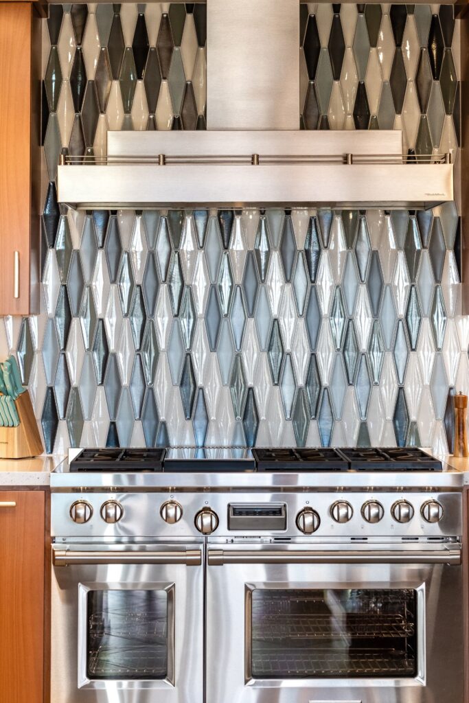 Kitchen range with stainless hood and geometric gray, white and blue tile backsplash