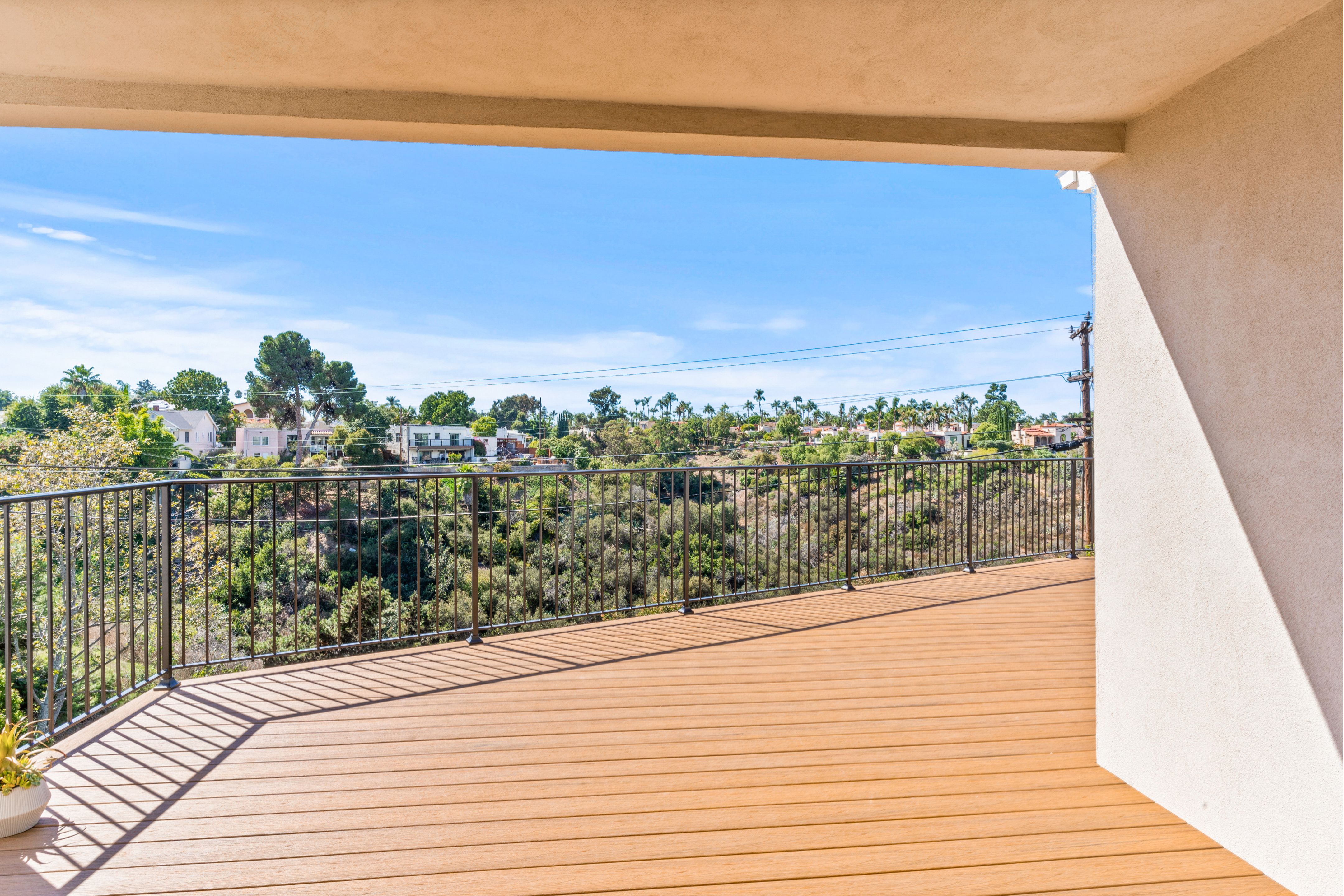 Cantilevered canyon deck with warm-toned decking, black metal railing and expansive neighborhood views