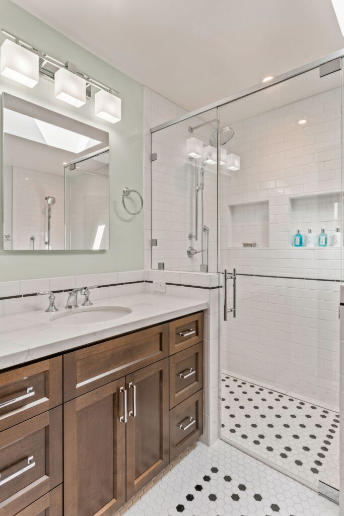 Bathroom with dark wood vanity, glass-enclosed shower, white subway tile and black-and-white hex floor
