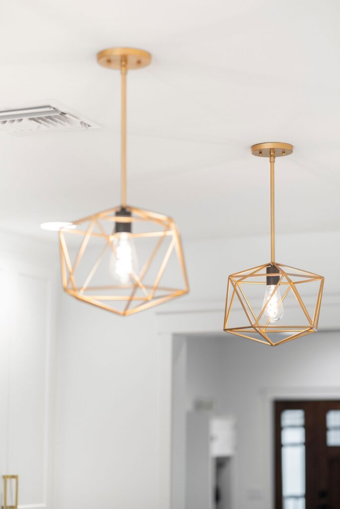 Brass geometric pendant lights with exposed bulbs suspended above the remodeled kitchen.