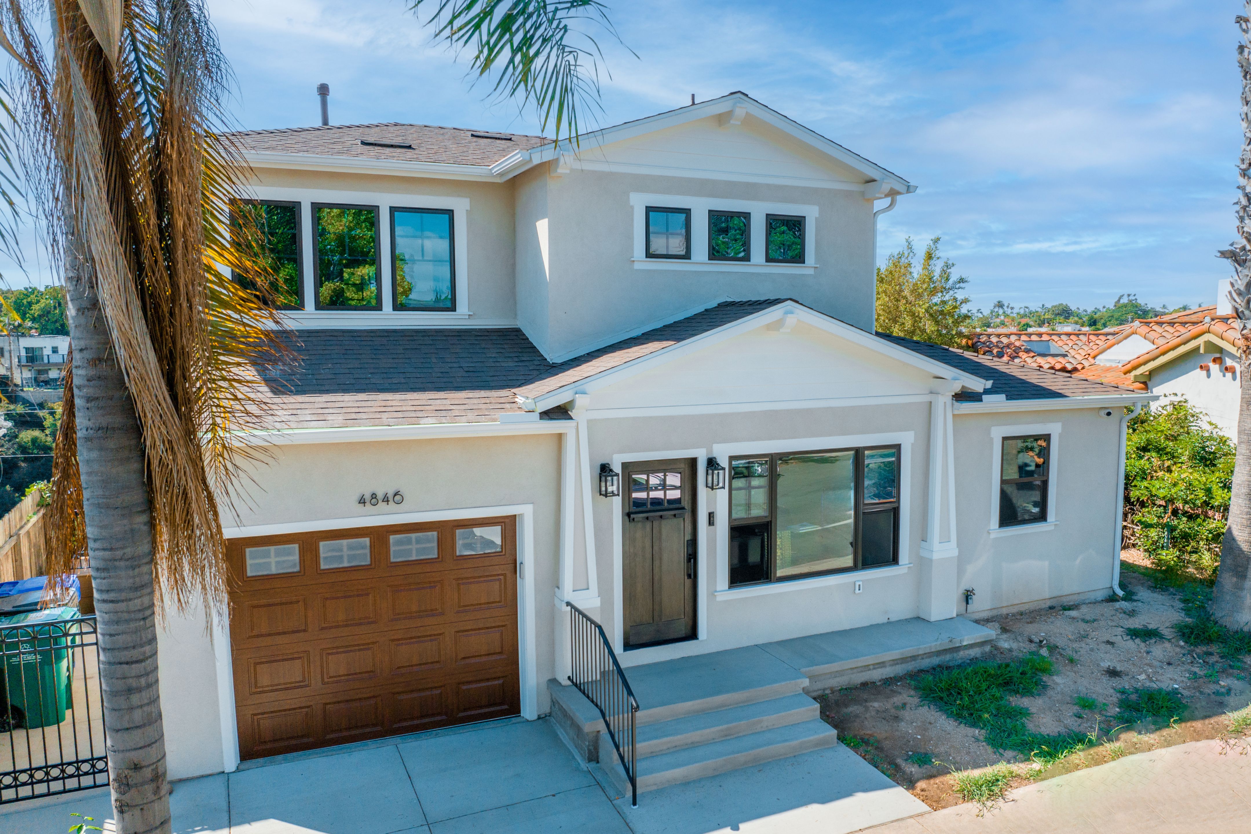 Two-story San Diego home with stucco exterior, gabled addition, dark-framed windows and wood-tone doors