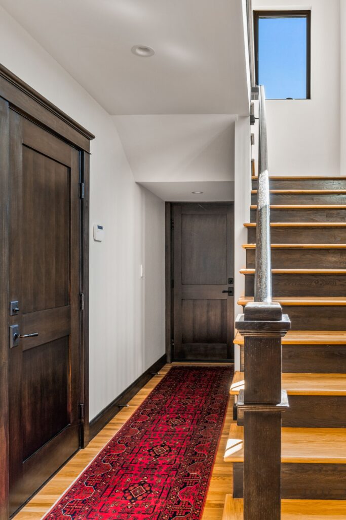 Interior staircase with stained wood trim, hardwood treads, dark wood doors and upper-level window