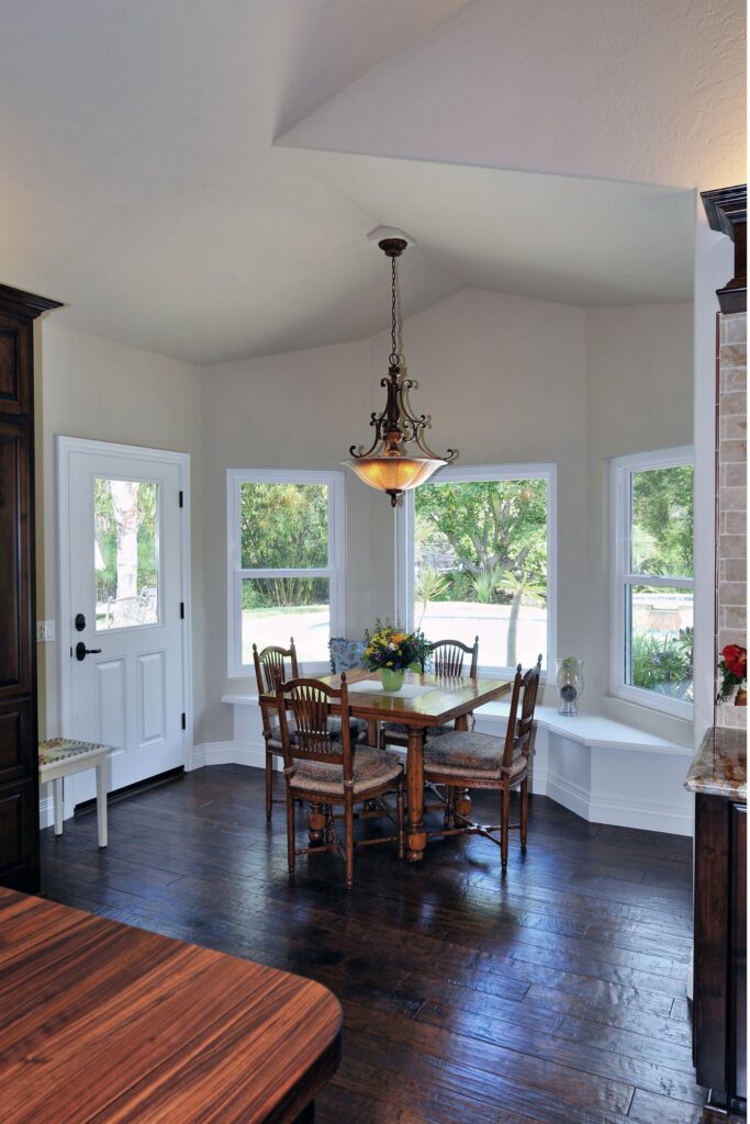 Breakfast nook with wraparound windows, built-in bench seating, dark wood floor and decorative chandelier