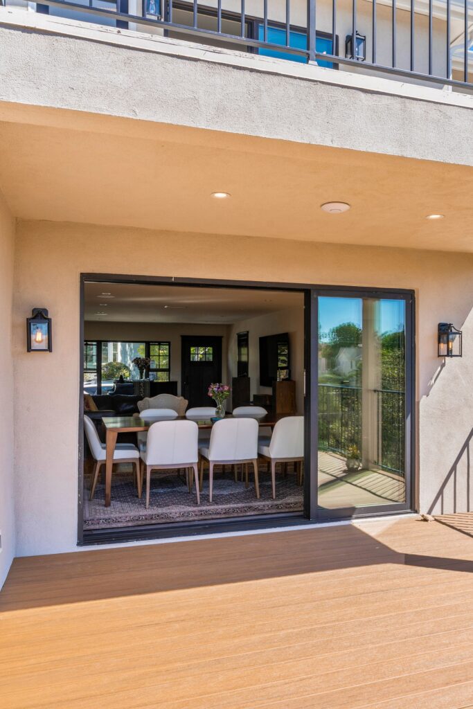 Canyon-facing deck with wood-look boards, stucco walls and wide sliding glass doors to the dining room