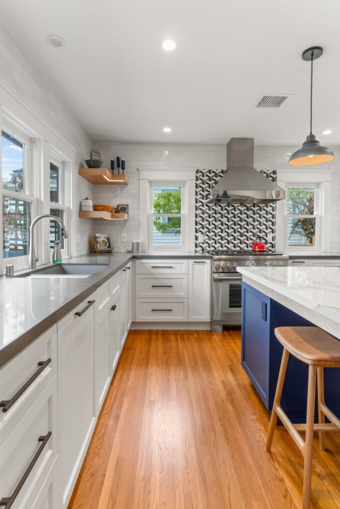 San Diego kitchen remodel with white cabinetry, blue seating island, stainless range, new windows and hardwood floors.