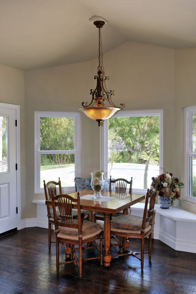 Breakfast nook with wraparound windows, built-in bench seating, dark wood floor and decorative chandelier