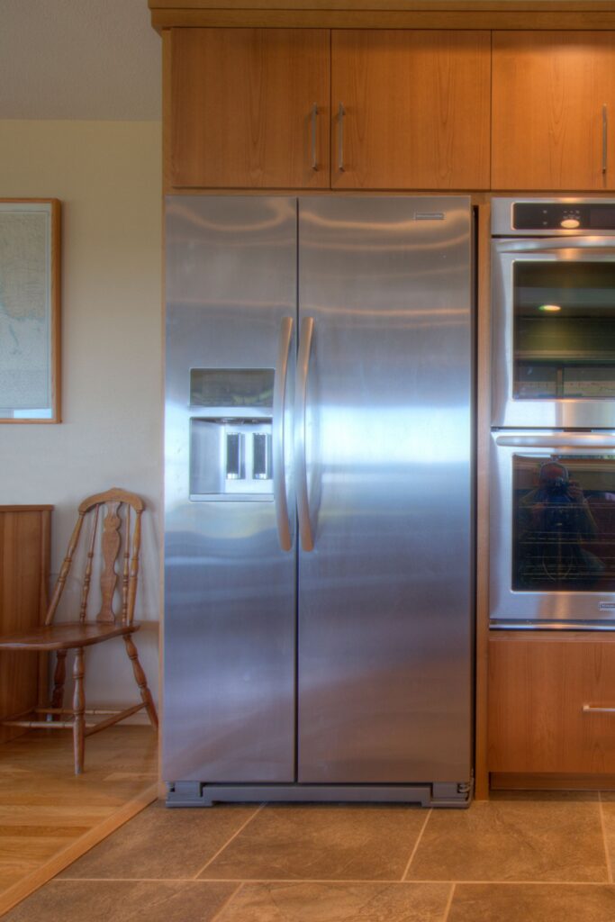 Stainless refrigerator and double wall ovens integrated into full-height wood kitchen cabinetry