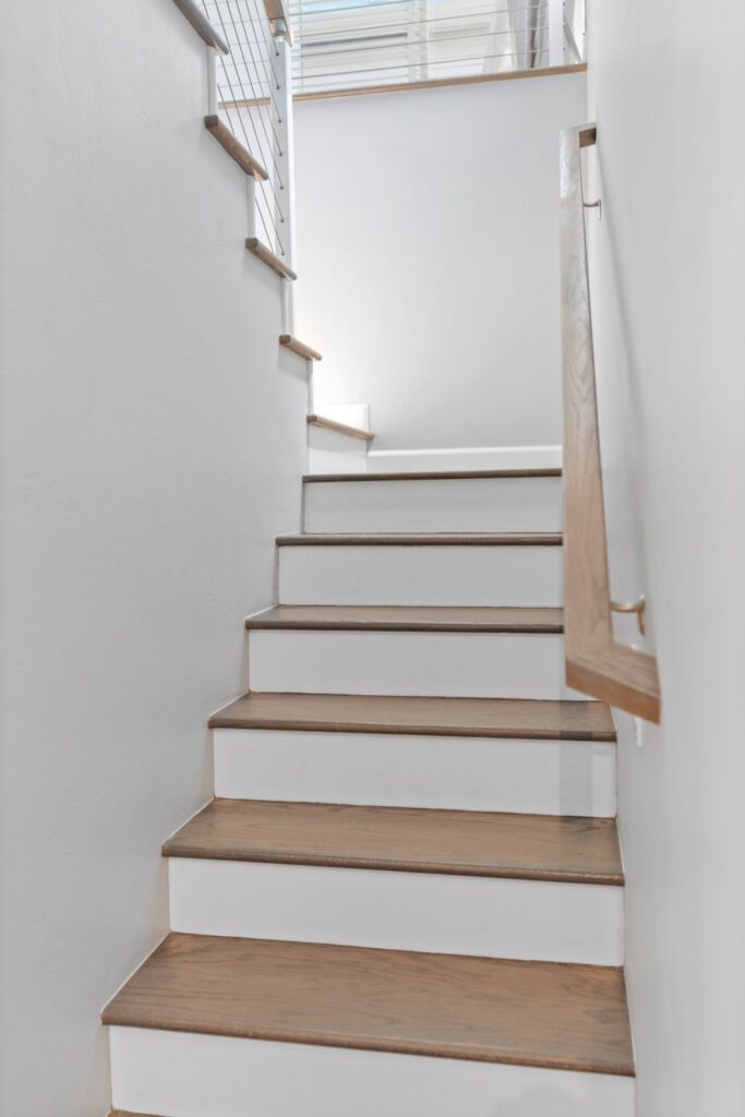 Remodeled staircase with wood treads, white risers, wood handrail and cable railing
