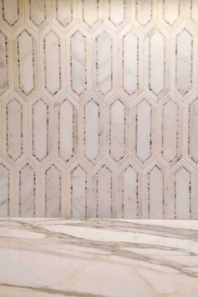 Close-up of geometric white and gray tile backsplash above a veined stone kitchen countertop