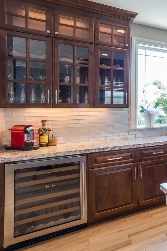 Kitchen beverage area with dark wood glass-front cabinets, granite counter, tile backsplash and built-in wine cooler.