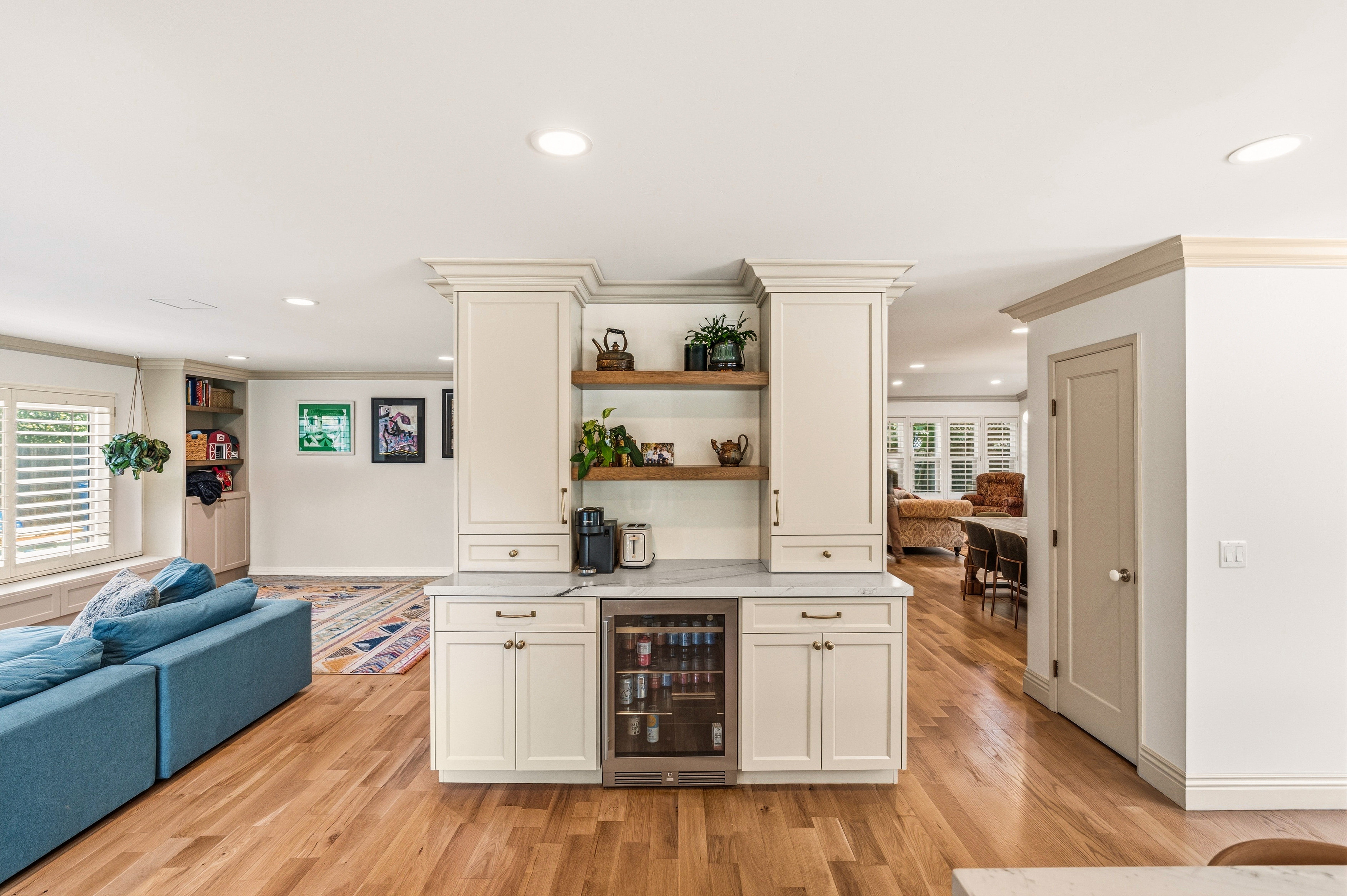 : Built-in beverage station with white cabinetry, wood shelves, stone counter and undercounter glass-front refrigerator.