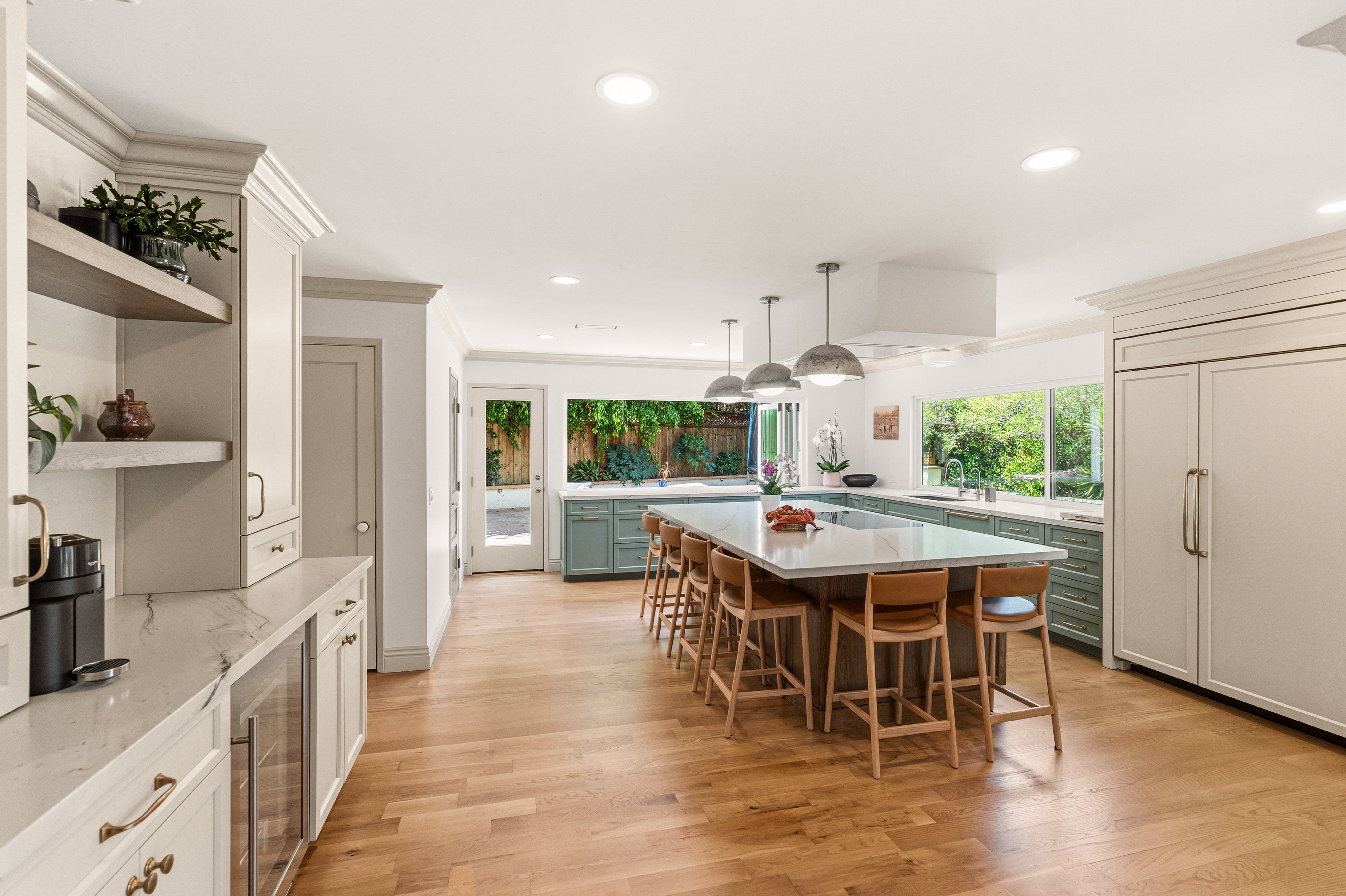 Large kitchen island with marble-look counter, wood stools, concrete pendants and a ten-foot bi-fold window.