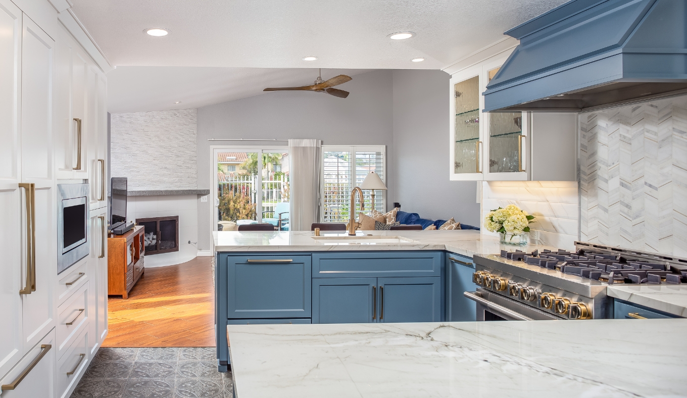 Open-concept kitchen remodel in Cardiff-by-the-Sea with blue cabinetry, a quartz island, brass fixtures and a view to the family room fireplace