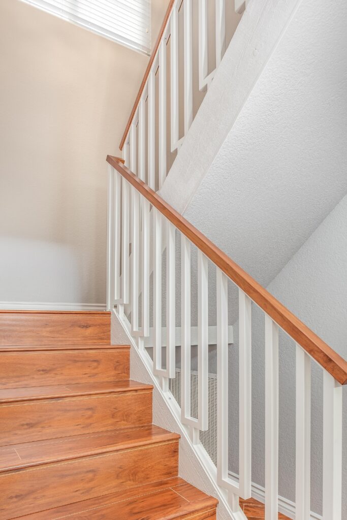 Staircase with painted white balusters and wood cap rail