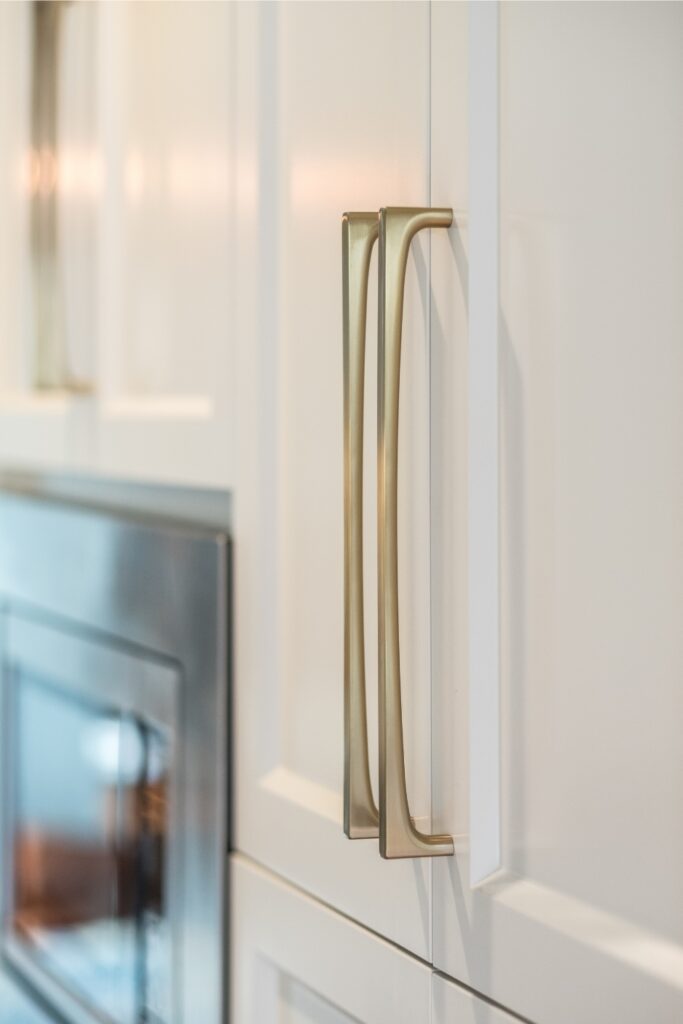 Vertical brass cabinet pulls on white kitchen cabinetry