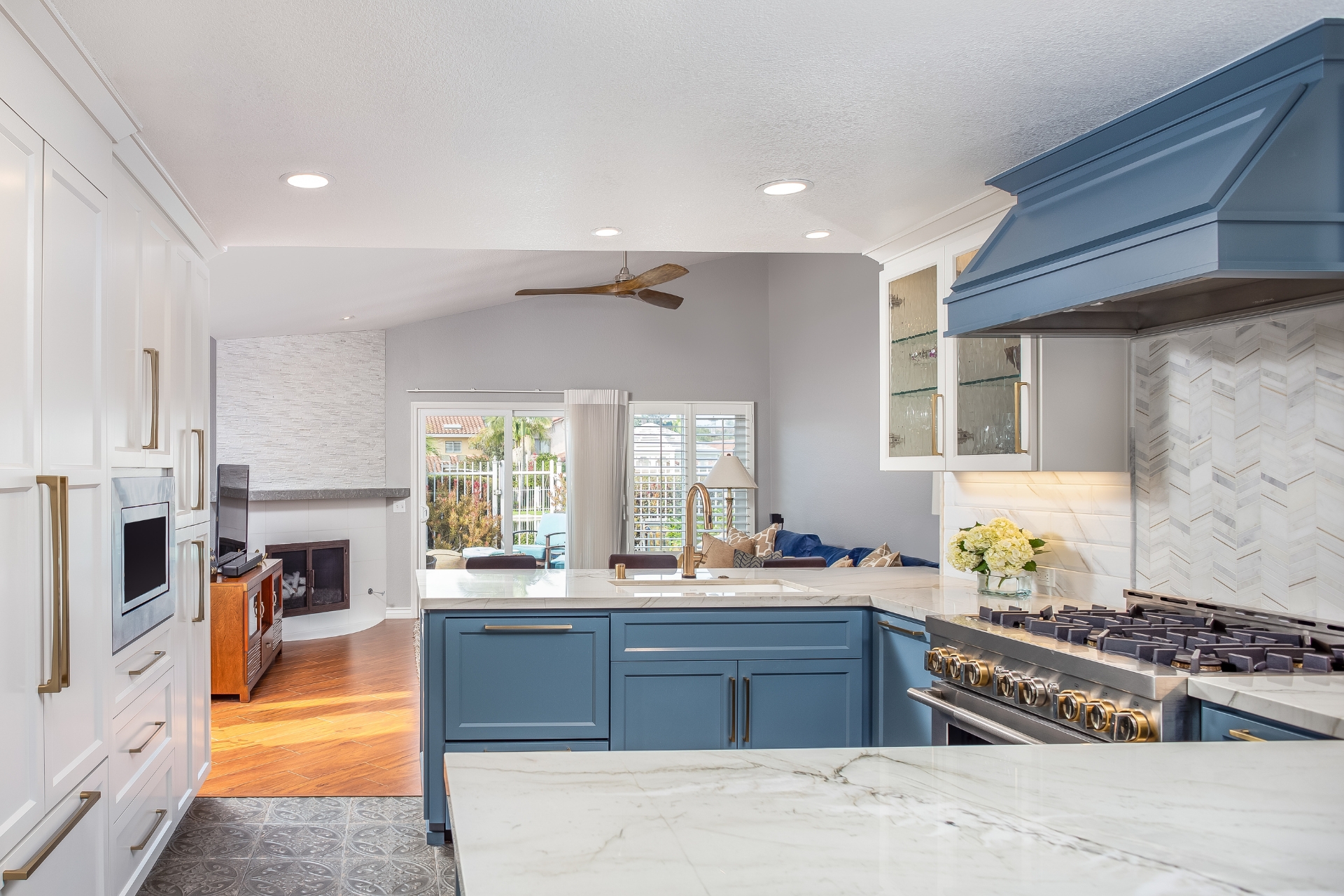 Open-concept kitchen remodel with blue island, quartz counters and view to family room fireplace