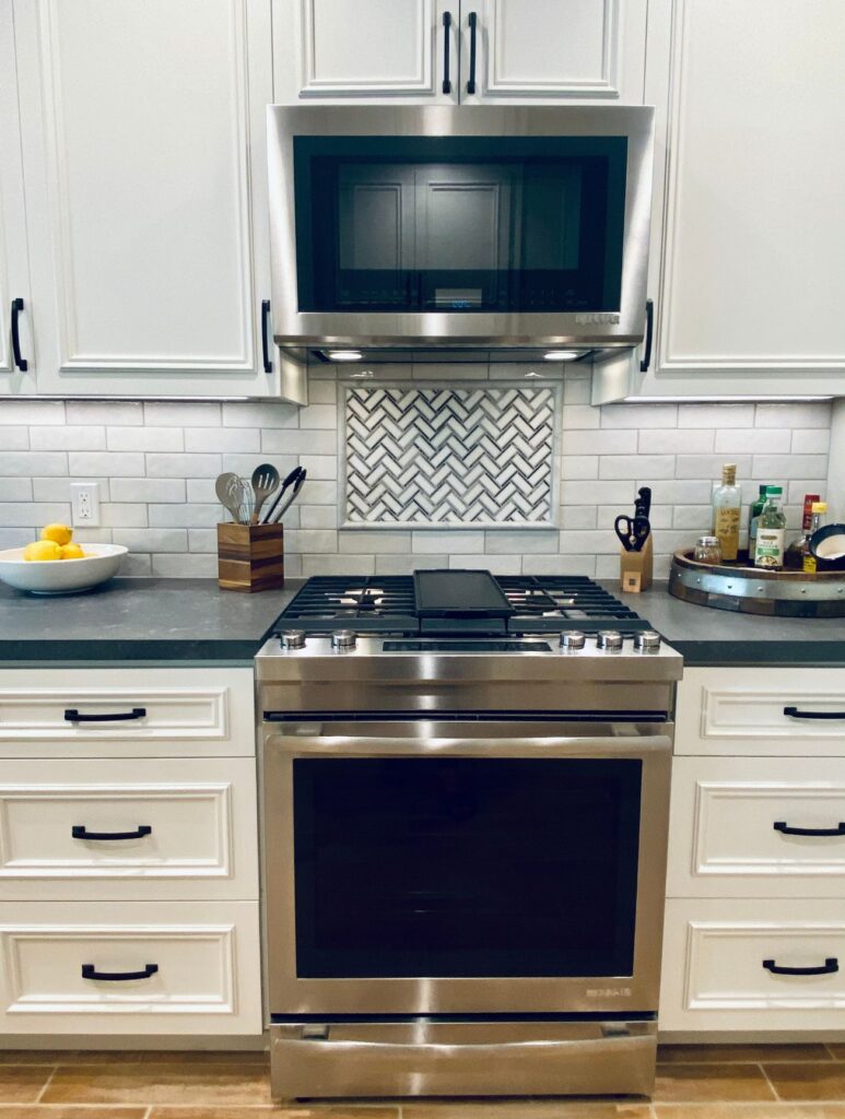 Carlsbad kitchen remodel with white cabinetry, apron-front sink, gray counters, wood shelving and subway tile backsplash.